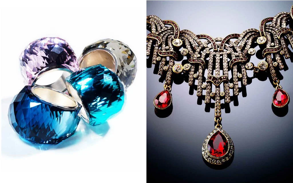 Collection of jewelry including large colored gemstone rings on the left and an ornate gold necklace with red gemstone pendant on the right.