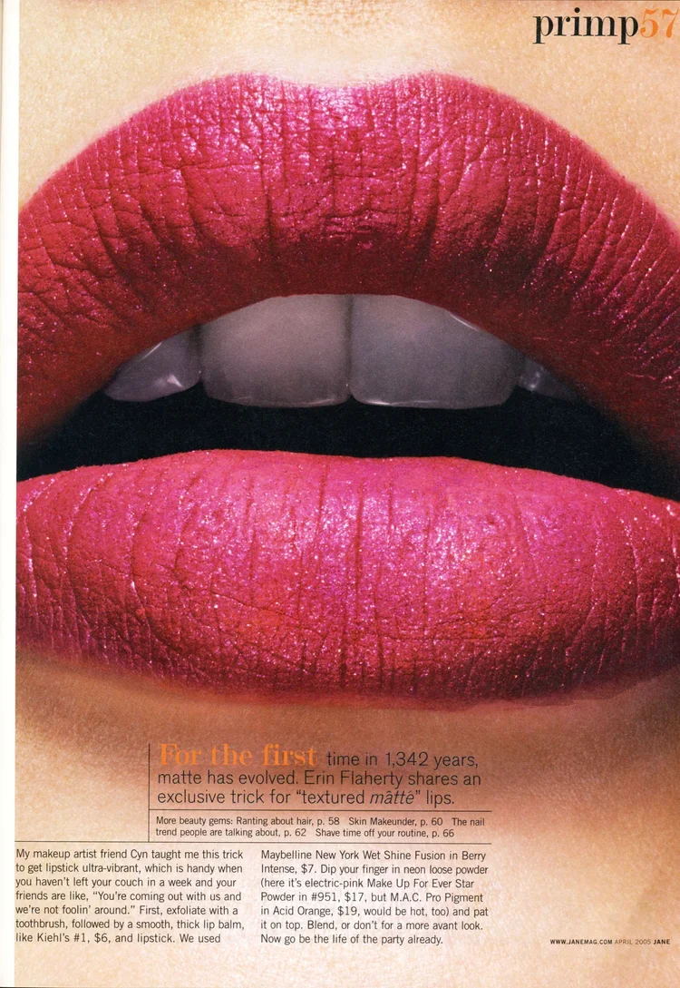 Close-up of lips with shiny, textured, matte pink lipstick, slightly parted revealing teeth, with a natural skin tone in the background.