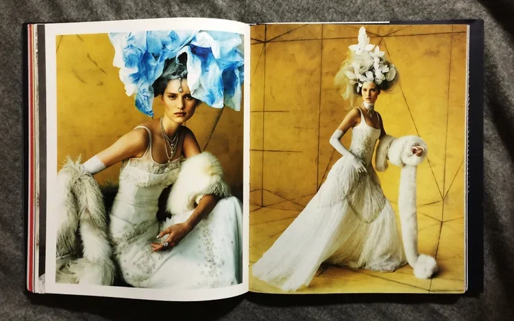 Fashion photos of a woman in elaborate white dresses with large, dramatic headpieces and accessories, set against a yellow background.