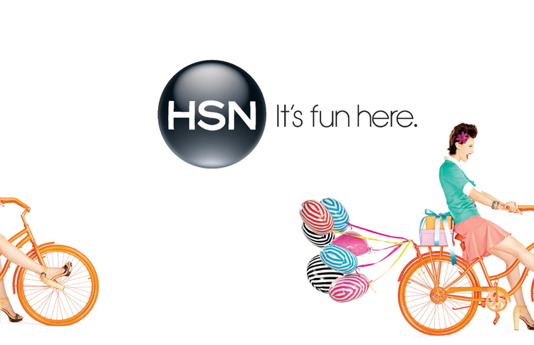 HSN logo with the slogan "It's fun here" and women riding orange bicycles, one with a side view of a woman pedaling on the left and another woman sitting on a bicycle on the right with balloons attached to the back.