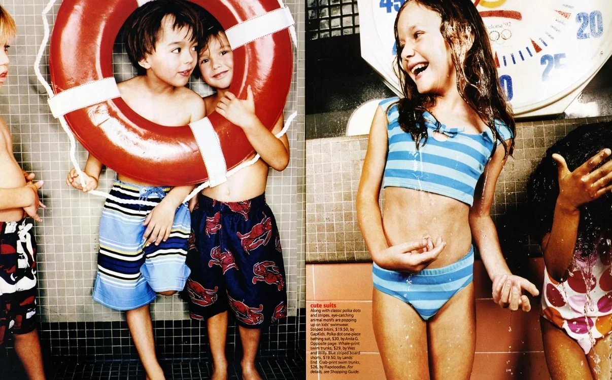 Children playing and laughing at a swimming pool, with one child wearing a life preserver and others in swimsuits, near a water clock.