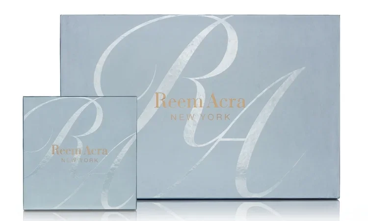 Two Reem Acra New York boxes, one large and one small, with a light blue background and gold lettering.