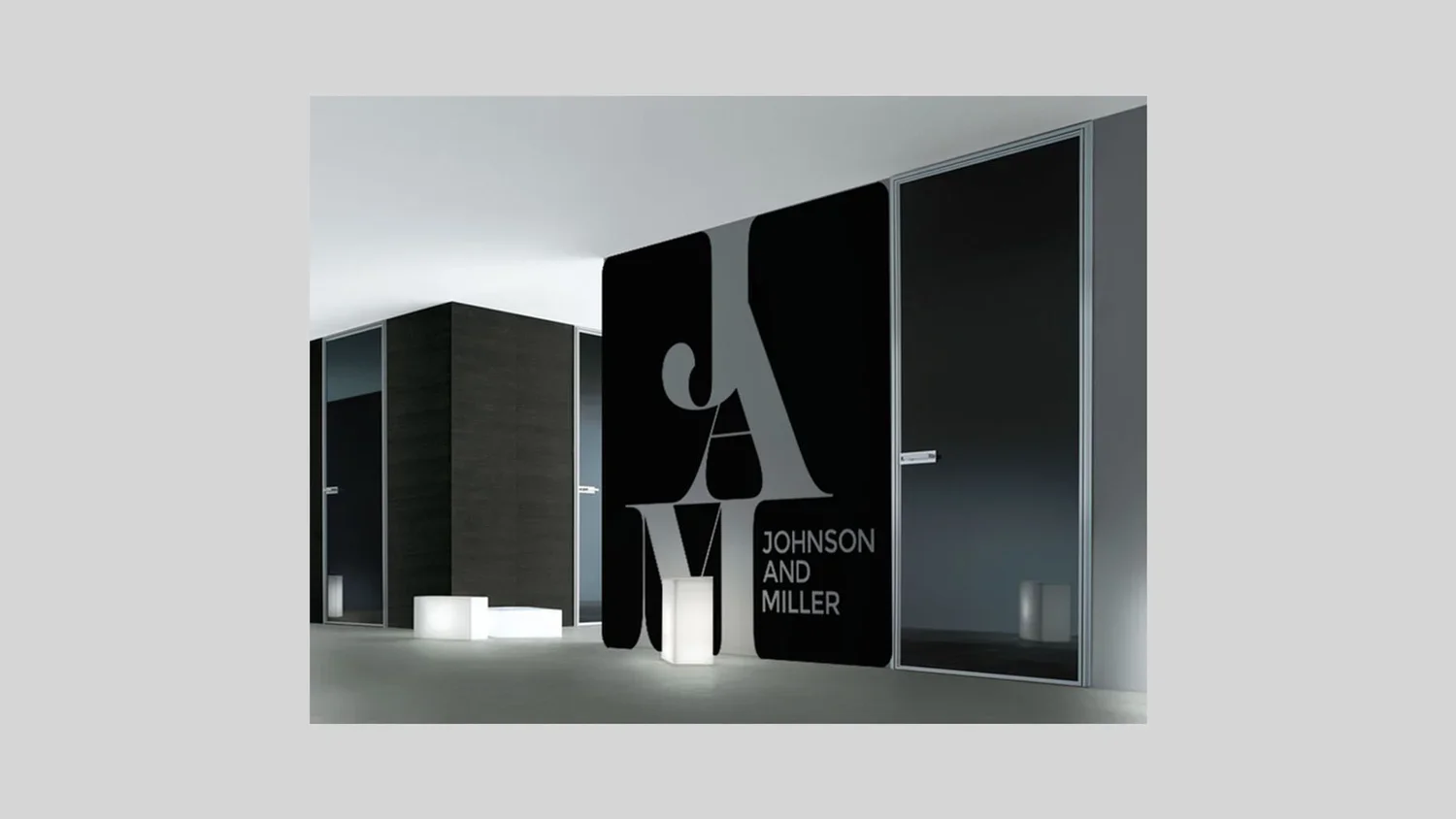 Modern interior turning hallway with black and gray walls, featuring the logo and name of Johnson and Miller on a large black panel.