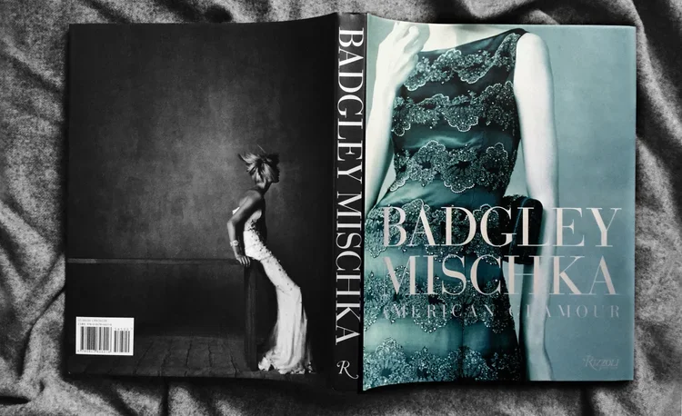 Open magazine titled 'Badgley Mischka' featuring a model in a teal lace gown on the cover and a black-and-white photo of a woman in a long dress on the inside page.