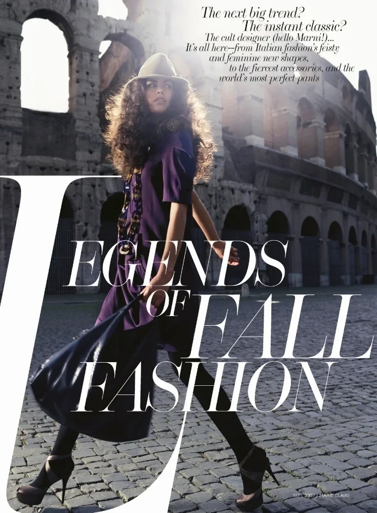 A woman with curly hair wearing a purple dress, black high heels, and a wide-brimmed hat walking in front of the Roman Colosseum, carrying a large black handbag, with overlaid text about fall fashion trends.