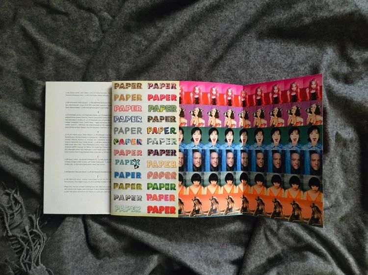 A colorful sheet with multiple strips of images of a woman, arranged in rows with different colors, alongside a white sheet of paper on a gray fabric background.
