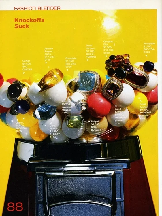 Close-up of a jewelry display with various rings, earrings, and bracelets arranged on a stand. The background is yellow with text advertising luxury brands and prices.