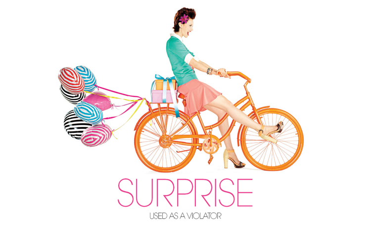 A woman riding an orange bicycle, carrying wrapped presents and balloons, with the text 'Surprise' and 'Used as a Violator' below.