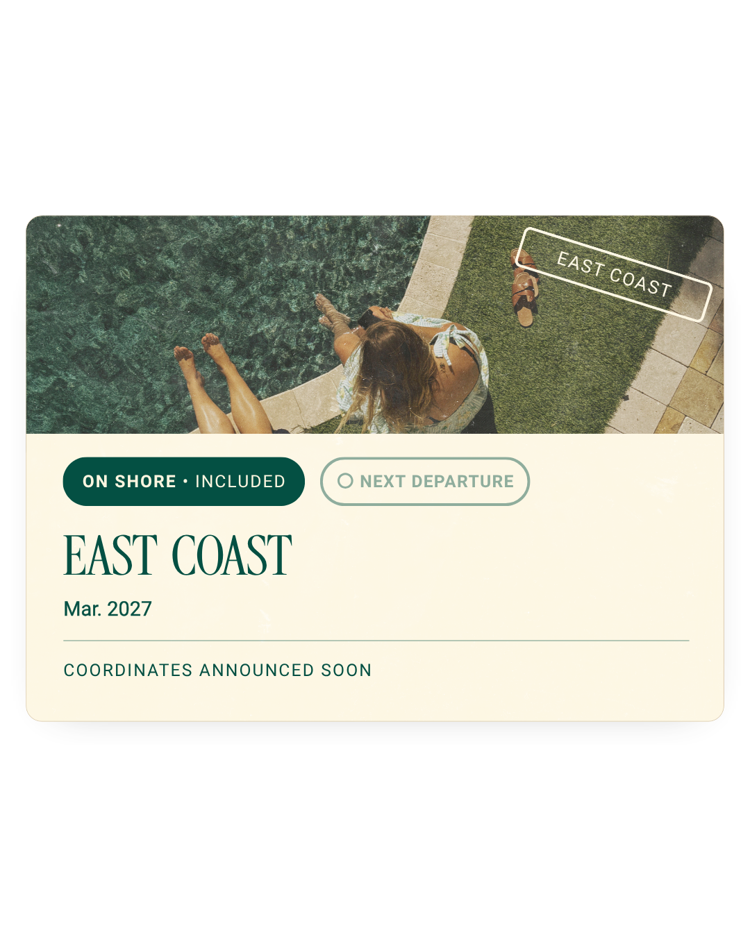 A person relaxing by a poolside with their legs in the water, near a sidewalk with a pair of sandals, with a sign reading 'EAST COAST' and a prompt for the next departure, onshore included, announcing East Coast travel in March 2027.