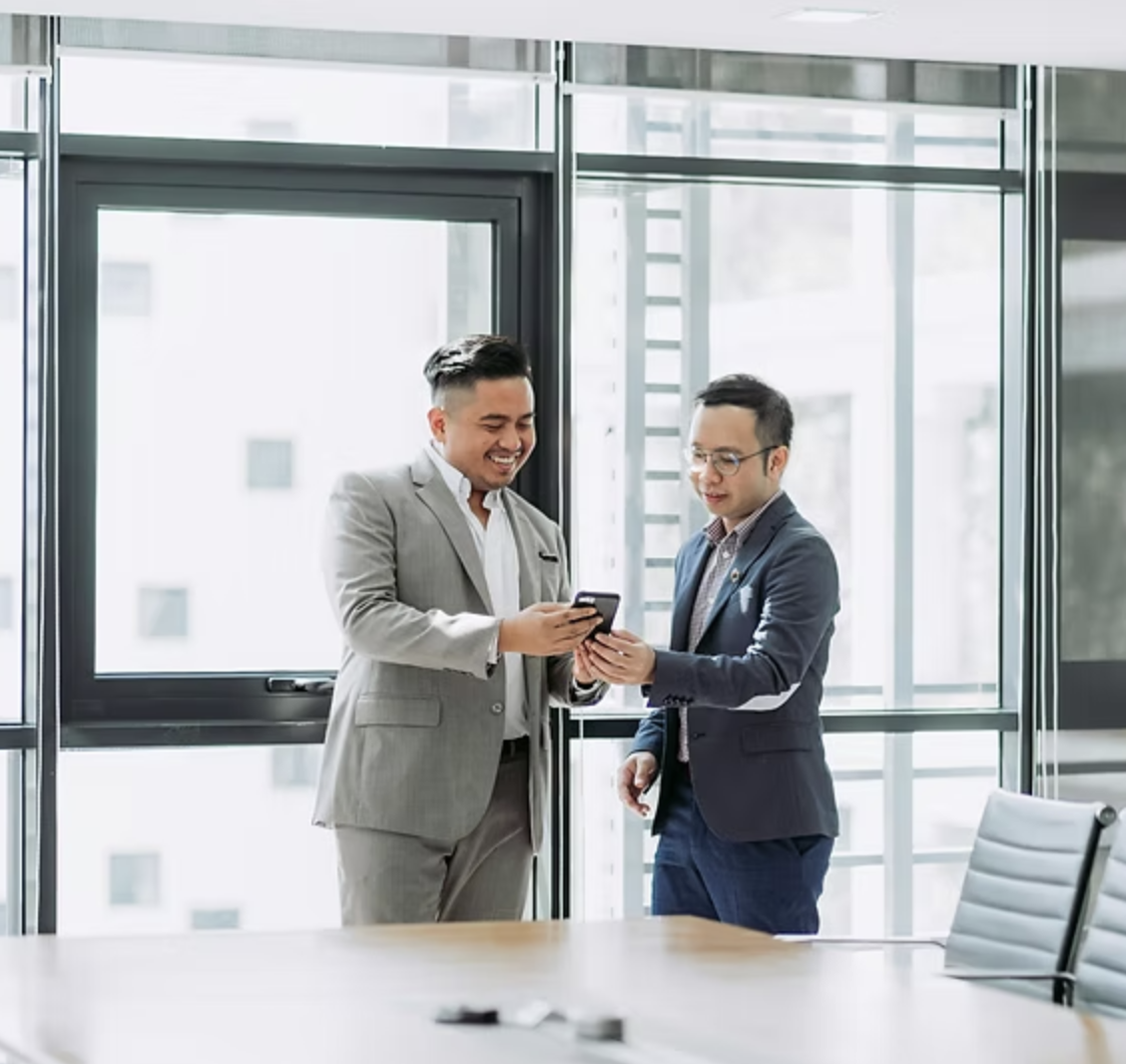 a cmo and a marketing director look at an phone screen in a brightly lit office