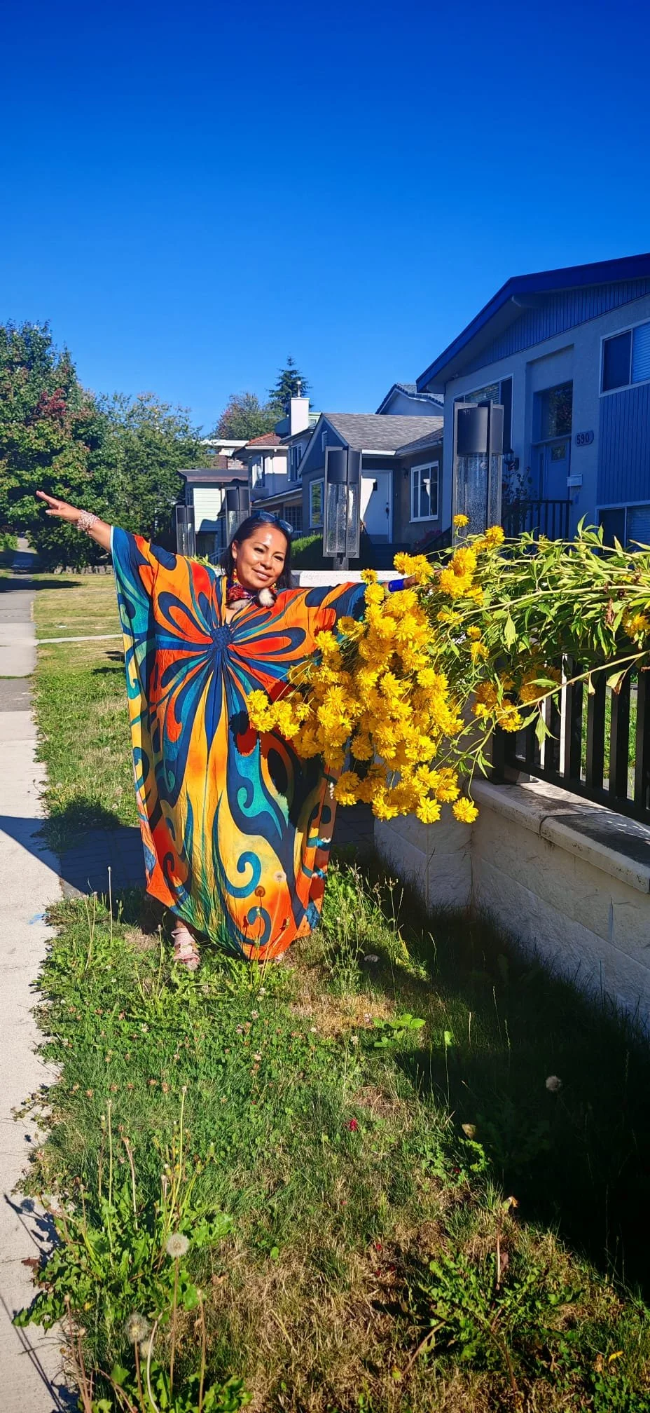 Samay Taki, Kichwa singer from the Ecuadorian Amazon, standing outdoors beside vibrant yellow flowers