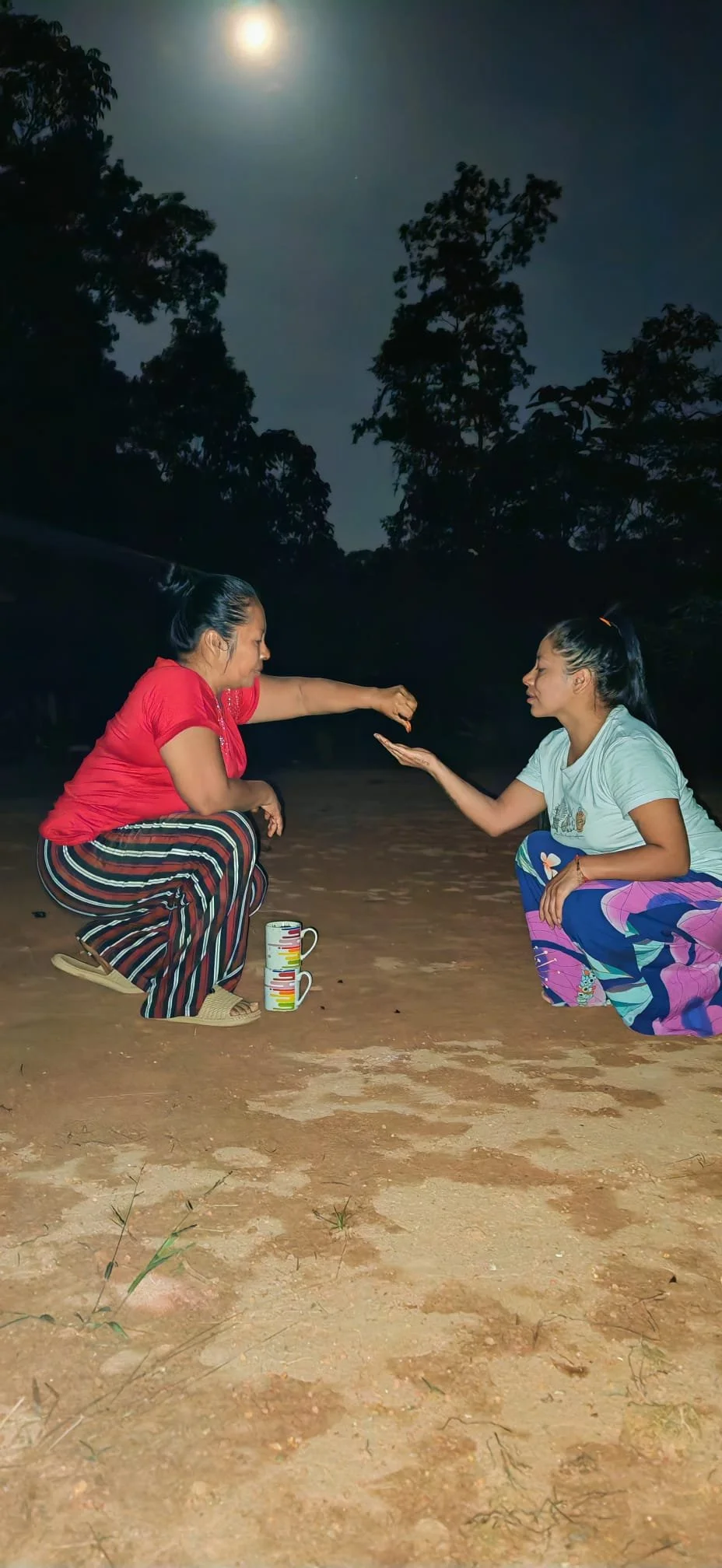 Samay Taki participating in an Indigenous ceremony outdoors at night beneath the moon and surrounding trees.