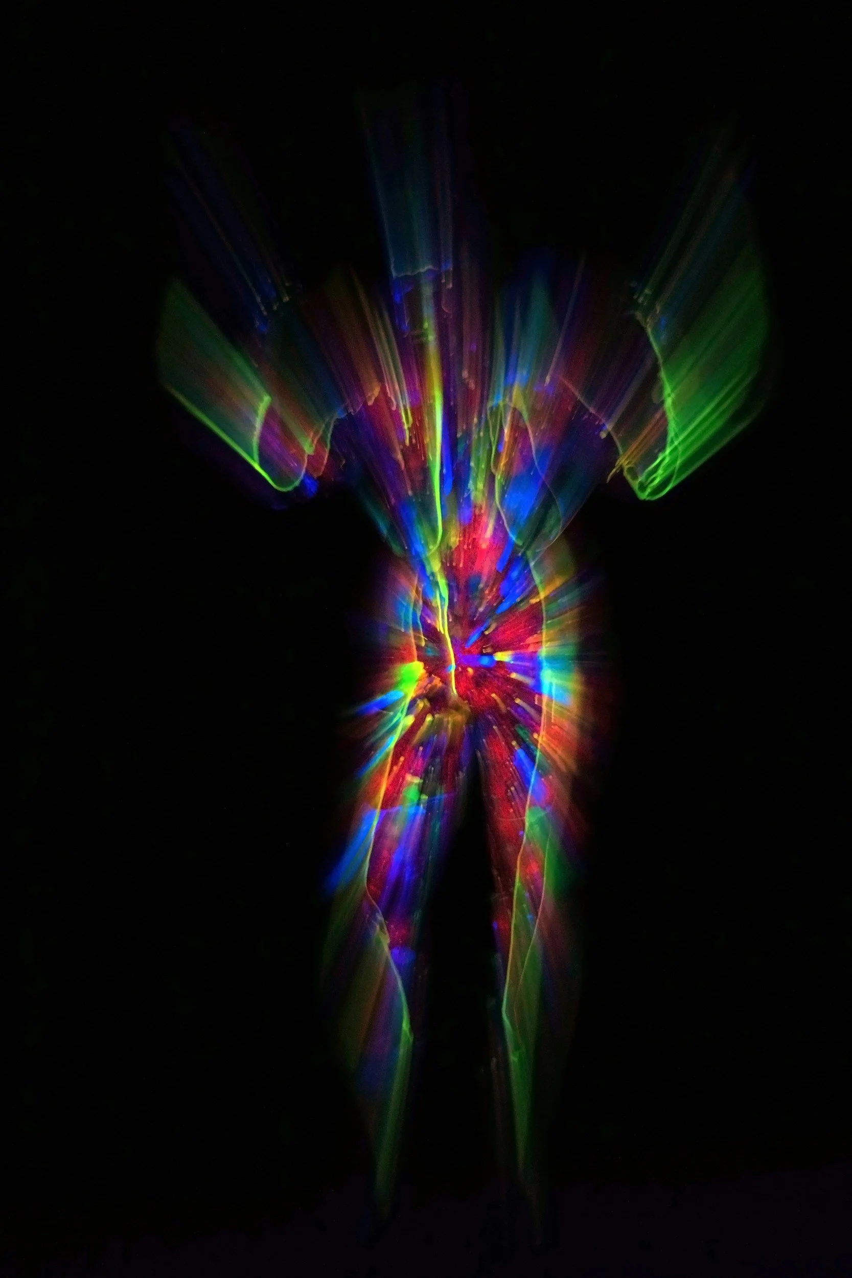 Colorful laser light display with rainbow hues and streaks of green, blue, red, and purple against a black background.