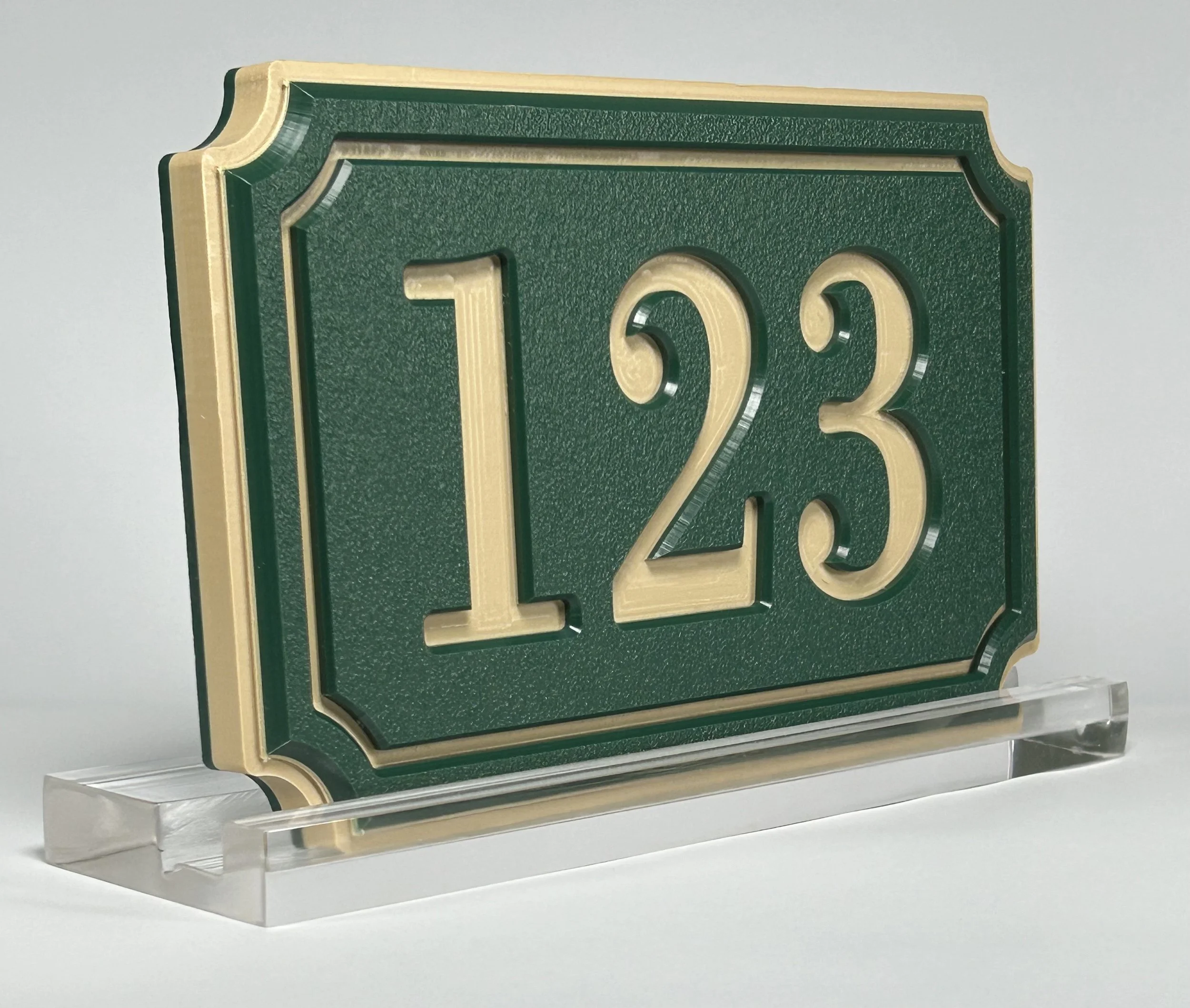 Close-up of a vintage-style green and gold metal sign with the number 73, mounted on a transparent stand.