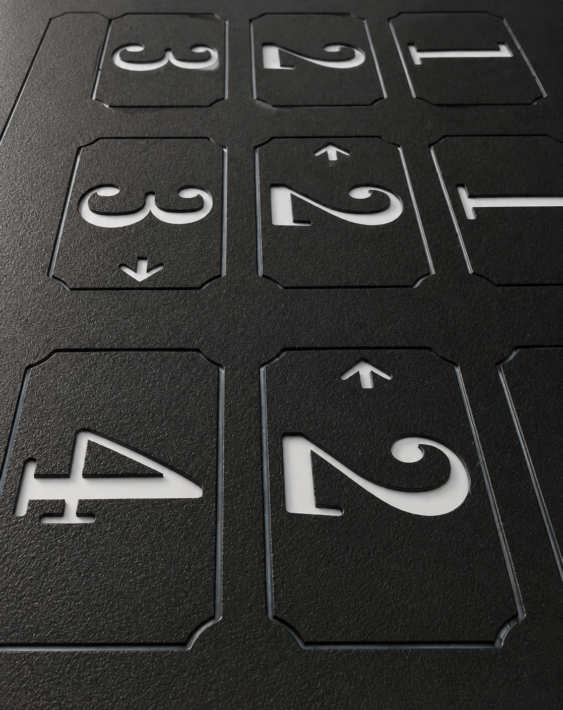 Close-up of a black textured board with white cut-out numbers '4', '2', '3', '1' and arrows indicating they can be rotated or flipped.