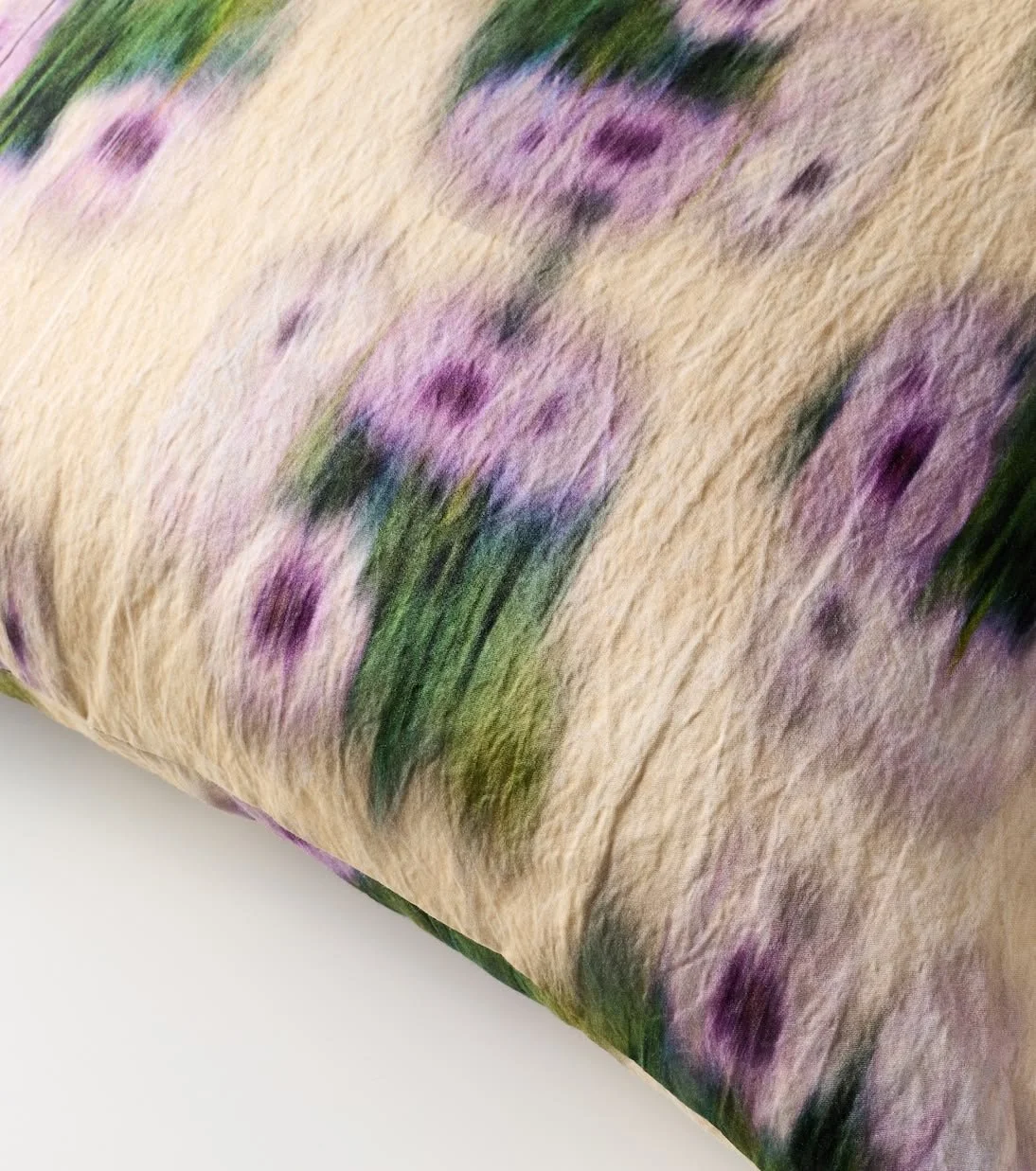 A close-up of a floral_pattern on fabric, featuring purple and green flowers on a beige background.
