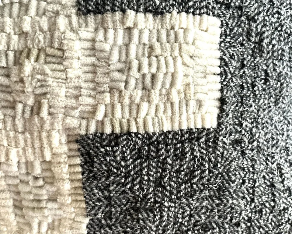 Detail of hand-hooked wool texture forming the Nordic cross motif.