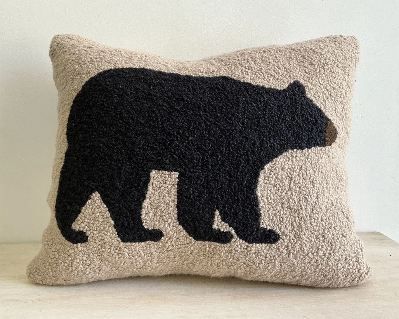Natural hand-hooked wool pillow with a black bear.