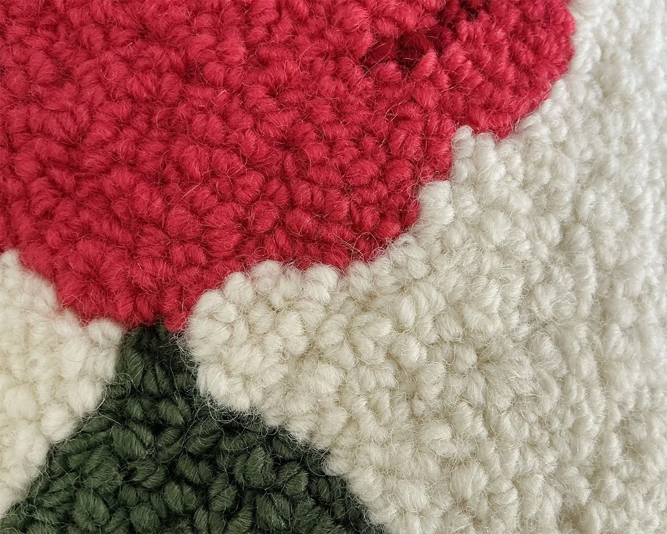 Mountain Bloom — Ivory hand-hooked wool pillow from the Meadowmark Collection, detail of densely looped crimson wool petals set against a warm ivory ground, with layered deep green leaves.