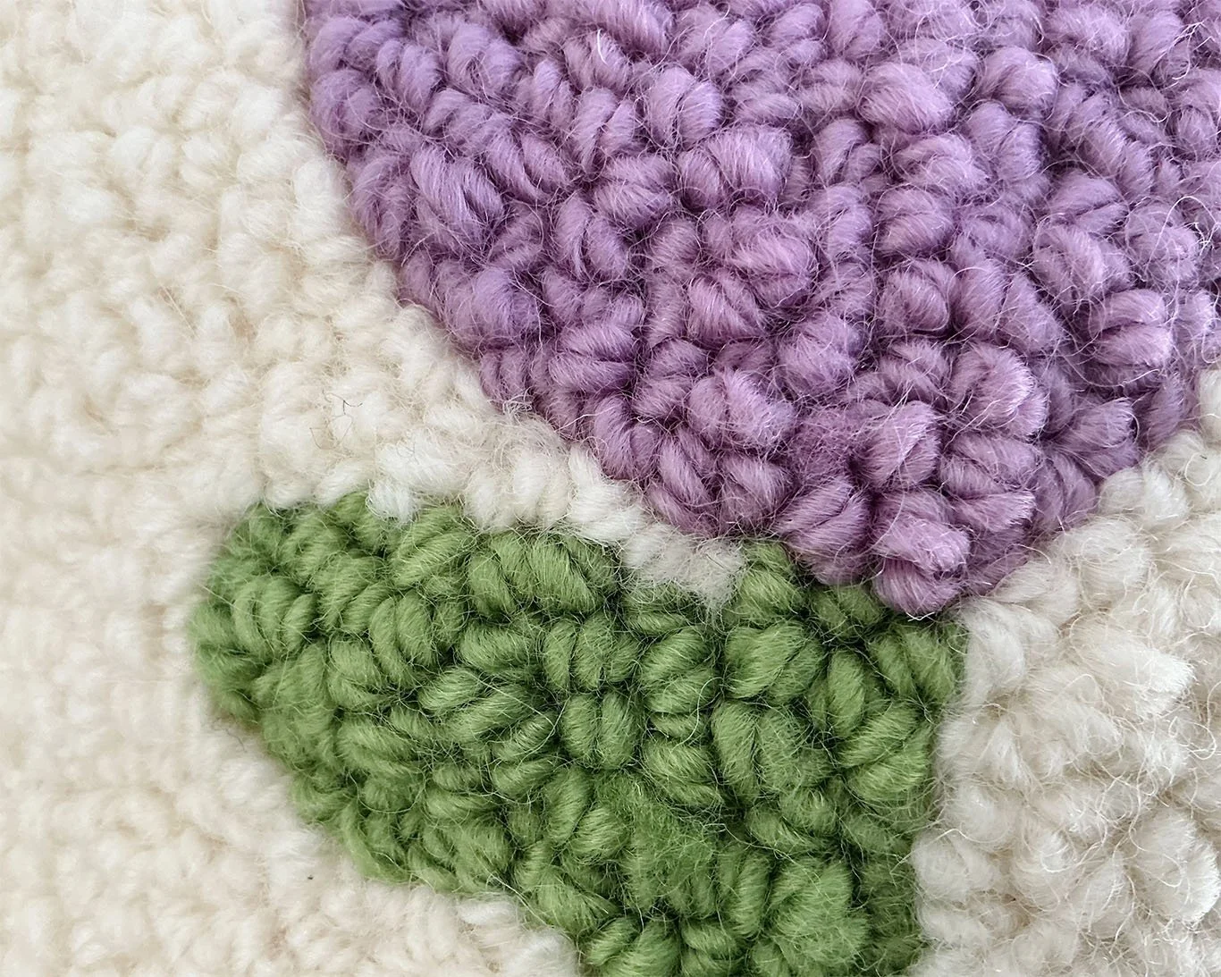 Detail of hand-hooked wool forming the stylized alpine flower motif.
