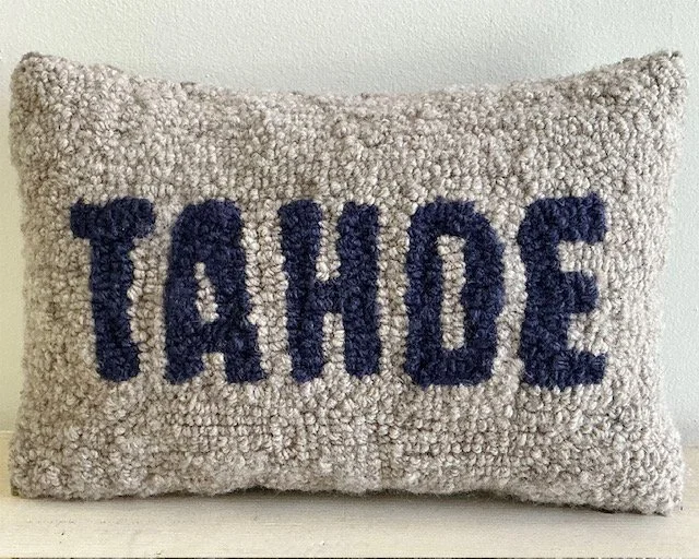 Hand-hooked wool pillow with the word "TAHOE" in indigo wool lettering on a natural stone-colored ground.