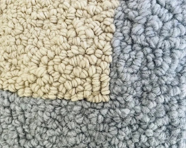 Detail of hand-hooked wool texture forming the gray blue geometric lines.
