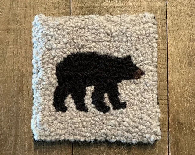 Hand-hooked wool panel featuring black bear silhouette on natural wool ground.