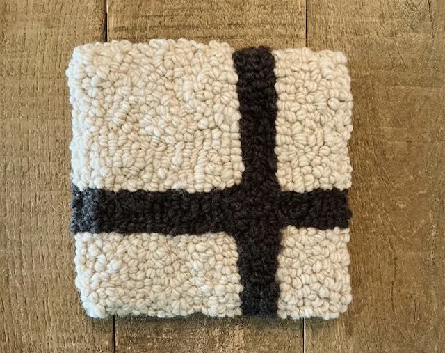 Front view of an oat hand-hooked wool panel with a dark umber cross motif.