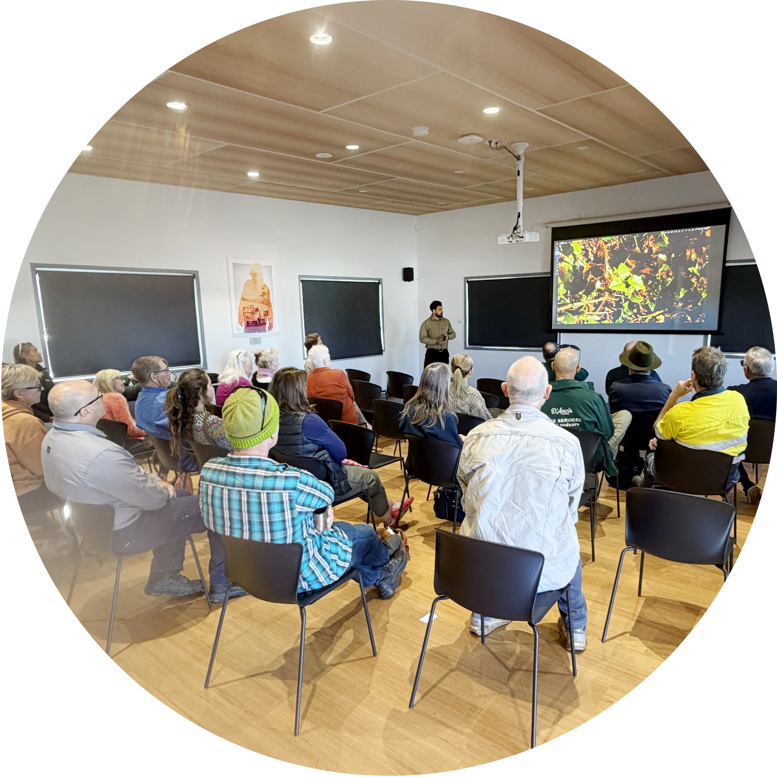 Audience seated in a meeting room while an NV Environmental team member delivers a presentation about the invasive species Madeira Vine.