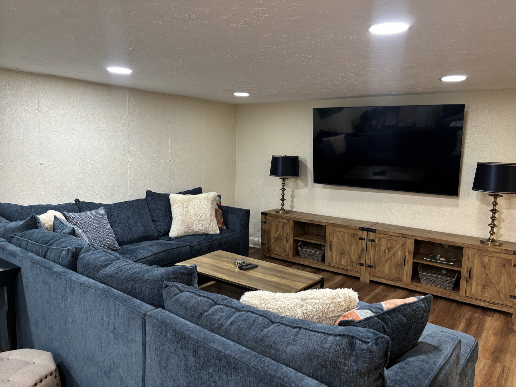 Main area of basement with large sectional and TV