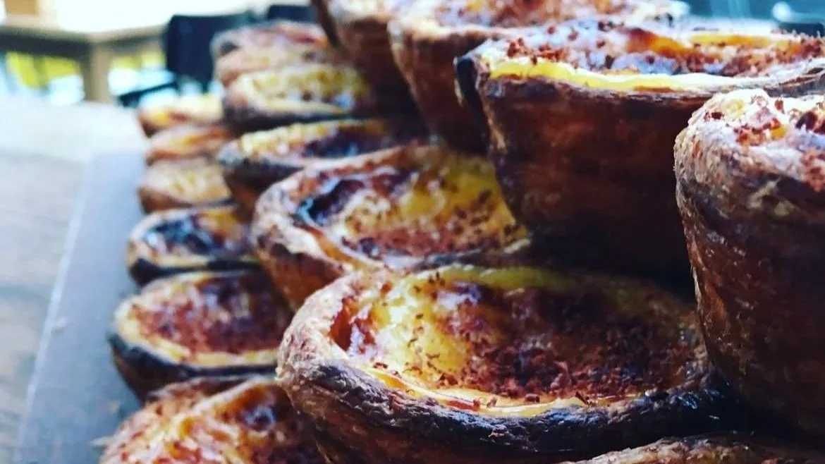 Close-up of several baked egg tarts with golden-brown crusts and creamy filling.