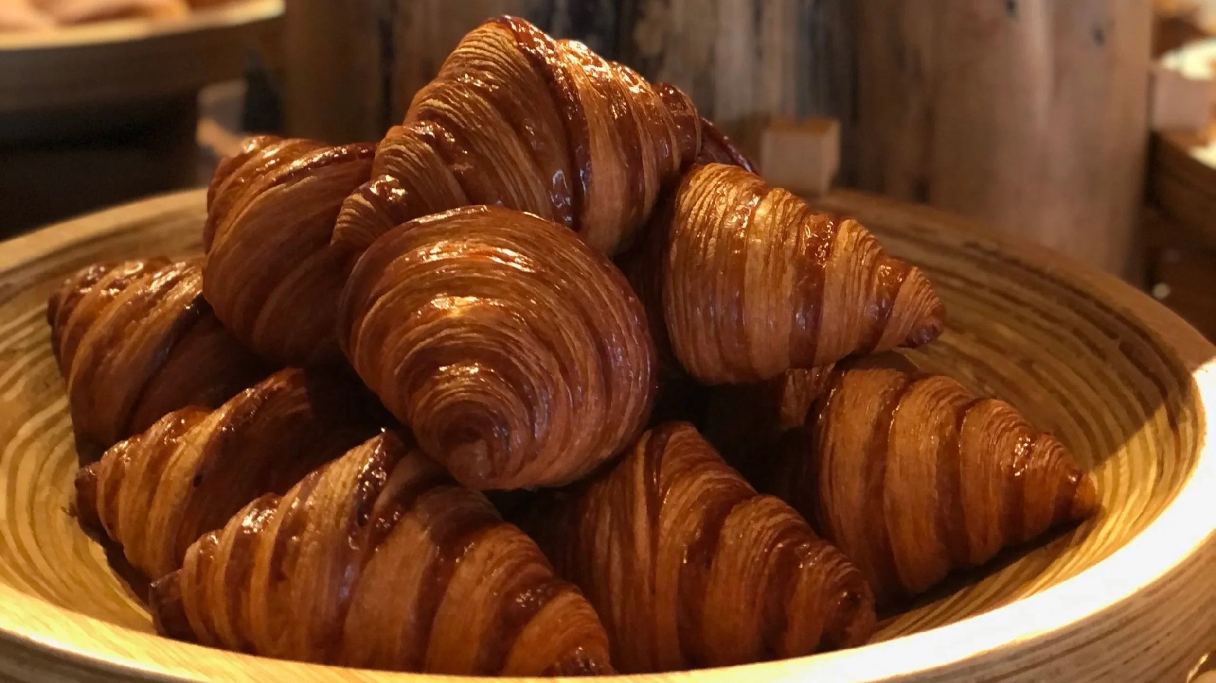 A bowl of freshly baked croissants stacked inside.