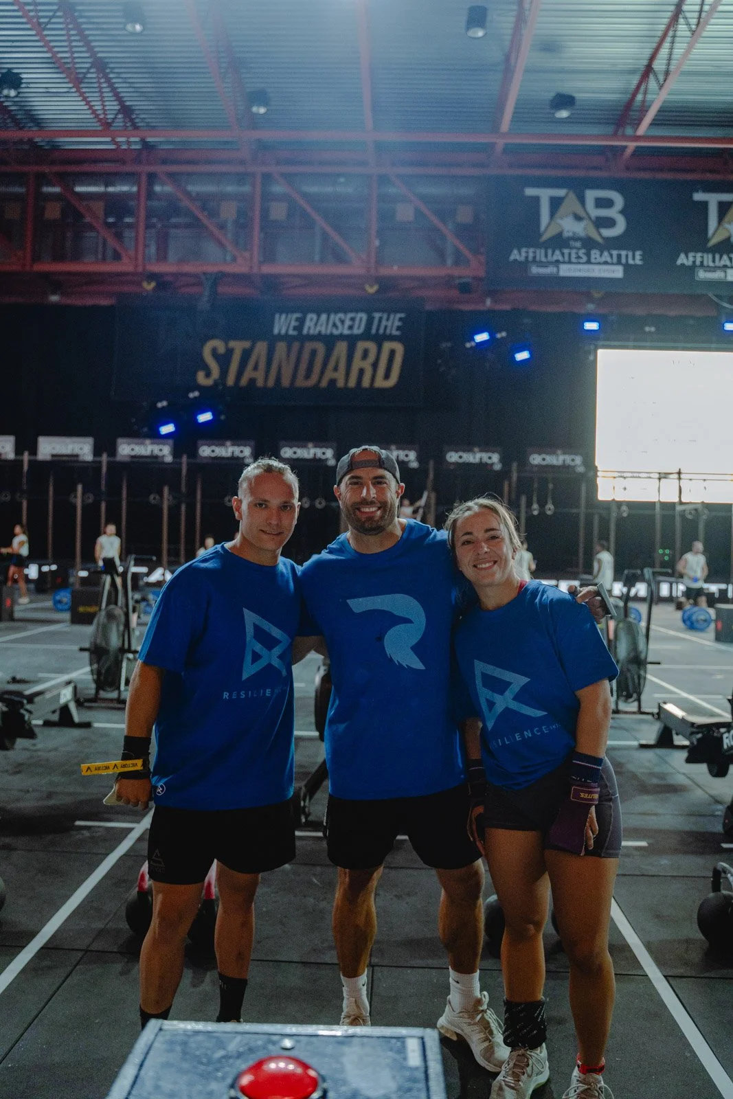 Trois personnes souriantes en t-shirts 'We Raised the Standard' lors d'une compétition CrossFit à Bordeaux — photographe CrossFit Voar by Tim