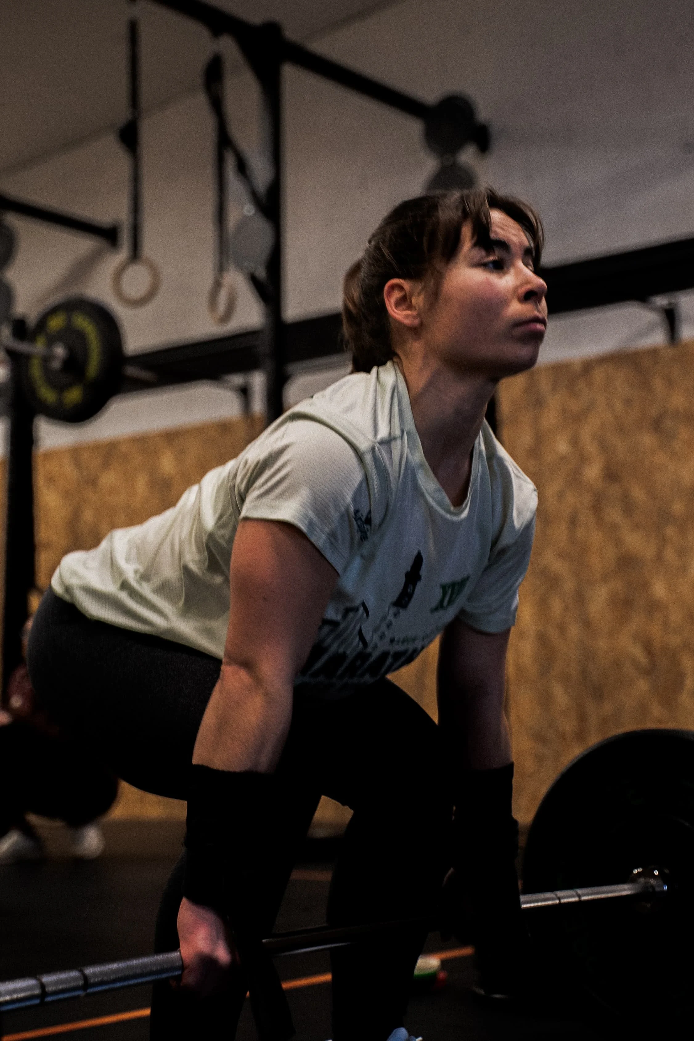 Une femme soulevant un poids lors d'une séance d'entraînement en salle de sport. Elle porte une tenue sportive et semble concentrée.