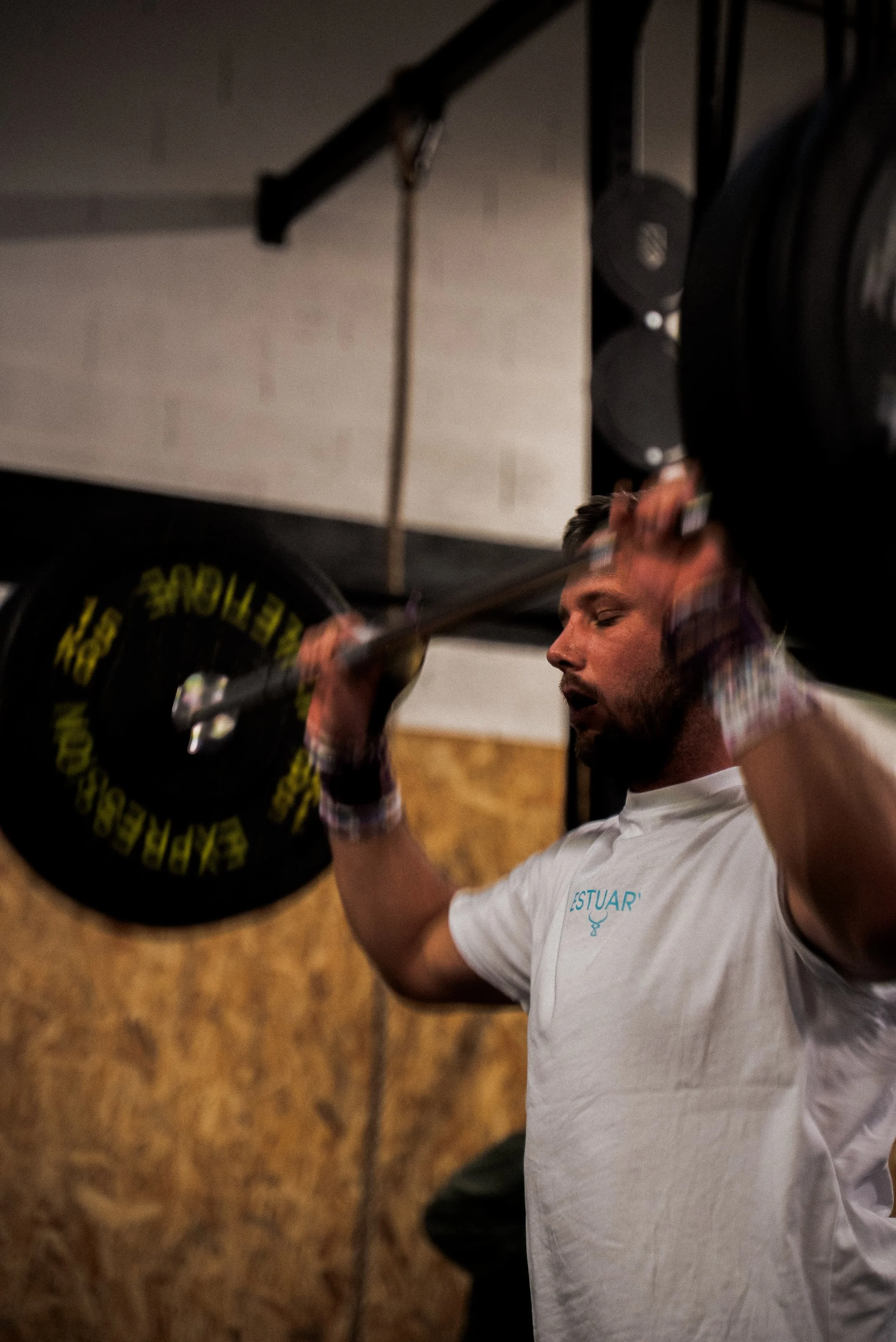 Homme soulevant une barre avec des poids dans une salle de gym. 