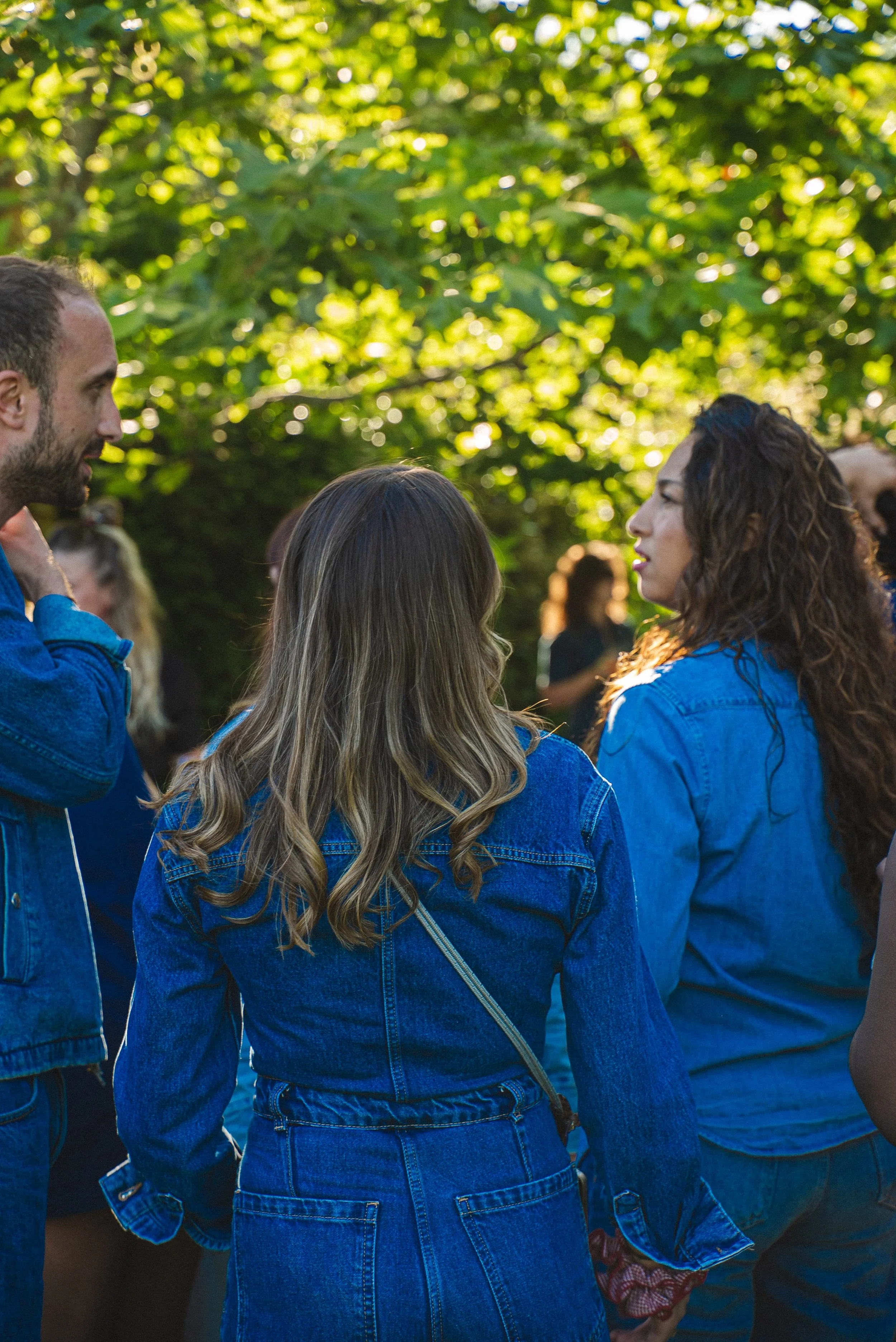 Groupe de personnes discutant lors d'un rassemblement en plein air avec des arbres en arrière-plan.