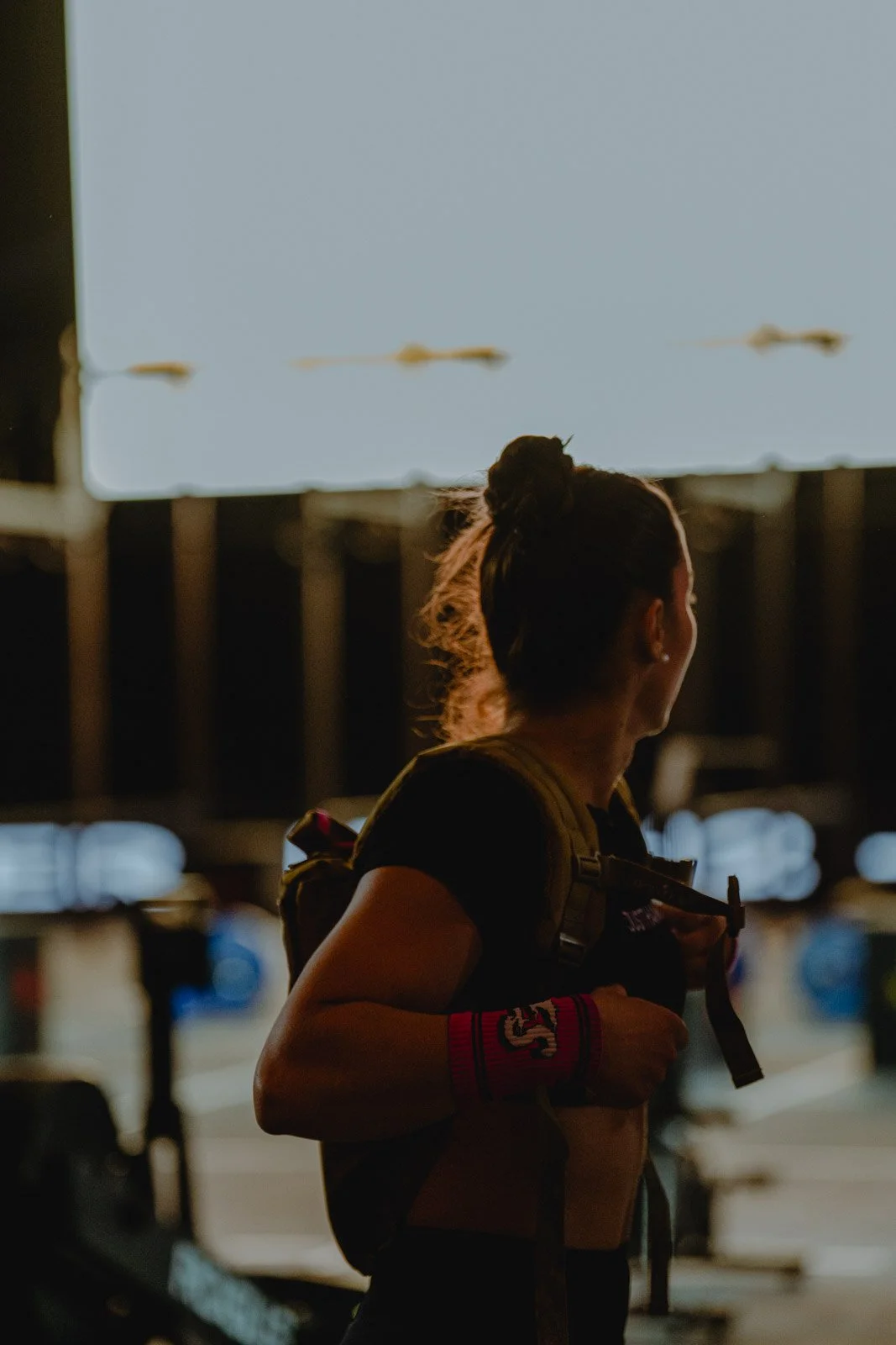 Femme avec sac à dos et bande de soutien au poignet, compétition CrossFit nocturne — photographe CrossFit Voar by Tim