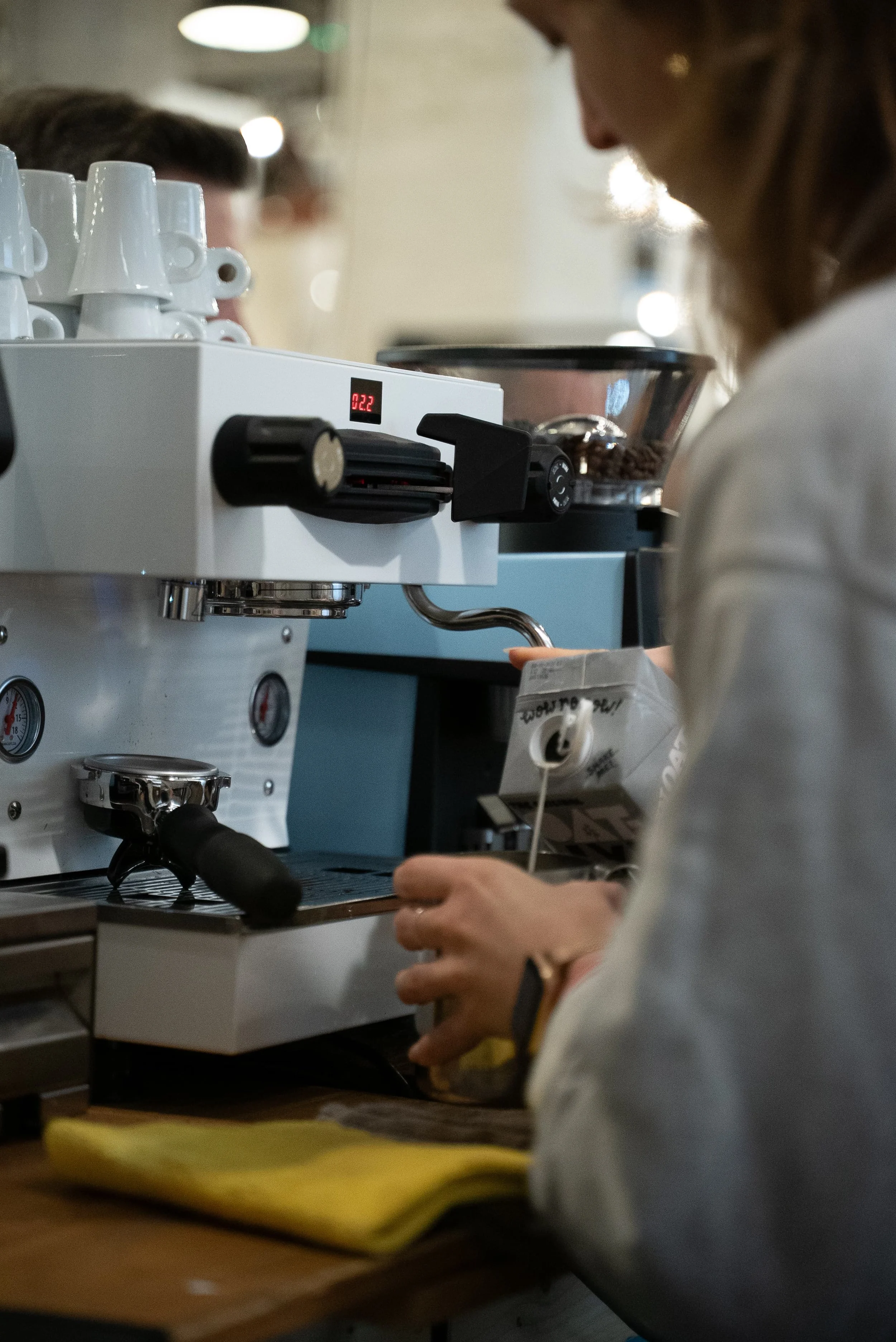 Une personne prépare un café ou un espresso dans une machine à café en utilisant une pince pour insérer la capsule ou le café moulu.