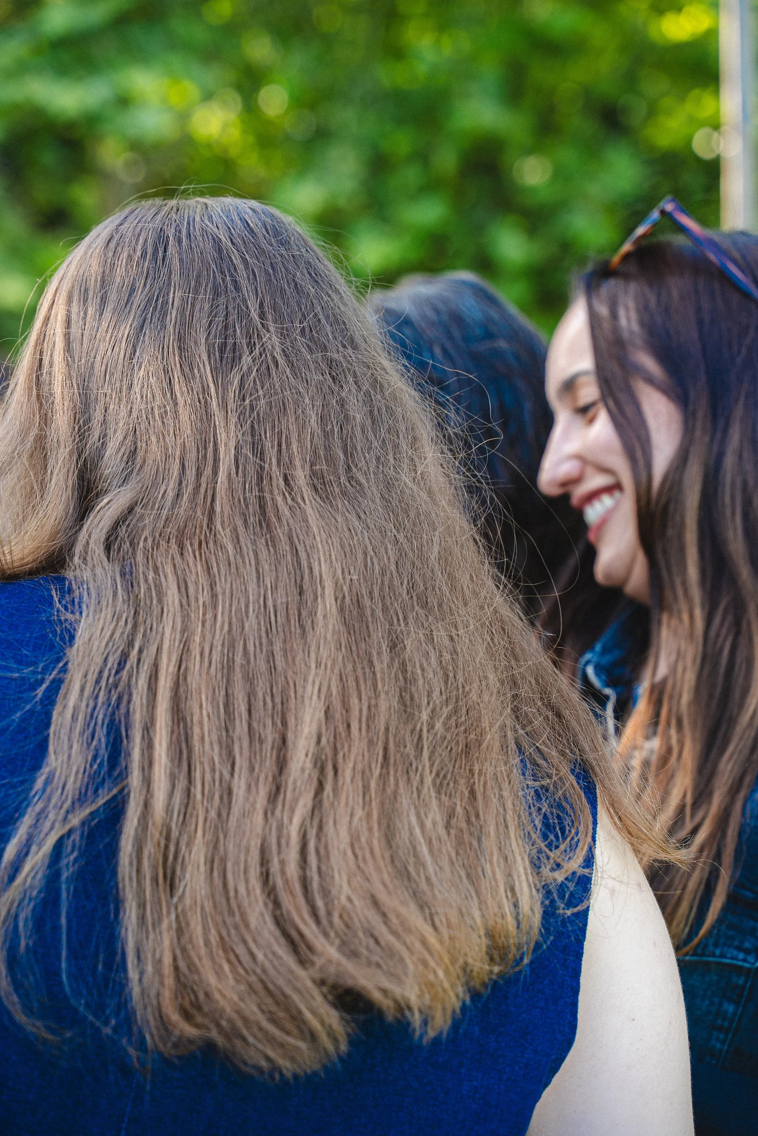 Groupe de personnes, principalement des femmes, partageant un moment de convivialité dans un espace extérieur avec des arbres en arrière-plan.