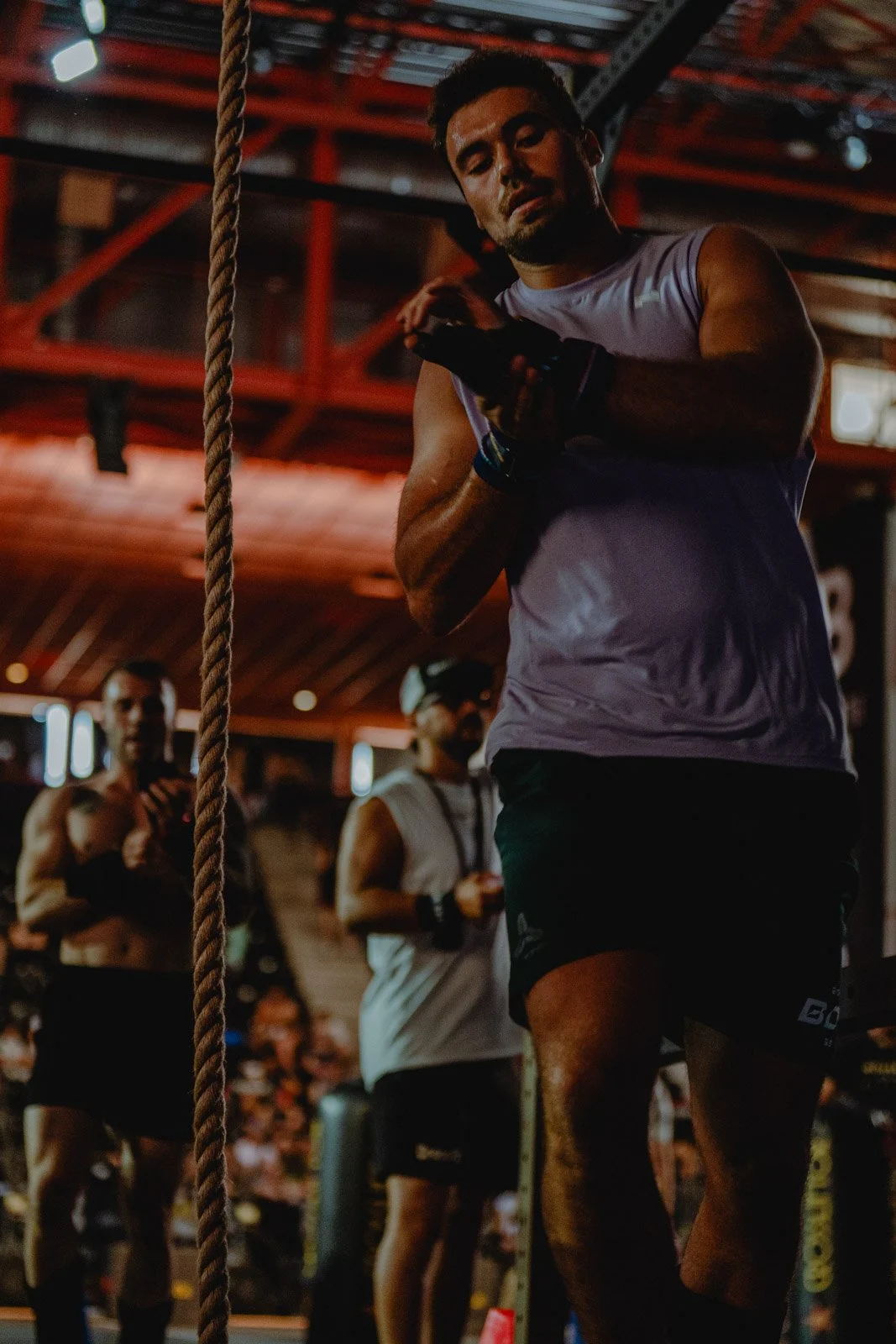 Homme en débardeur regardant son téléphone dans une salle CrossFit avec d'autres athlètes — photographe CrossFit Voar by Tim