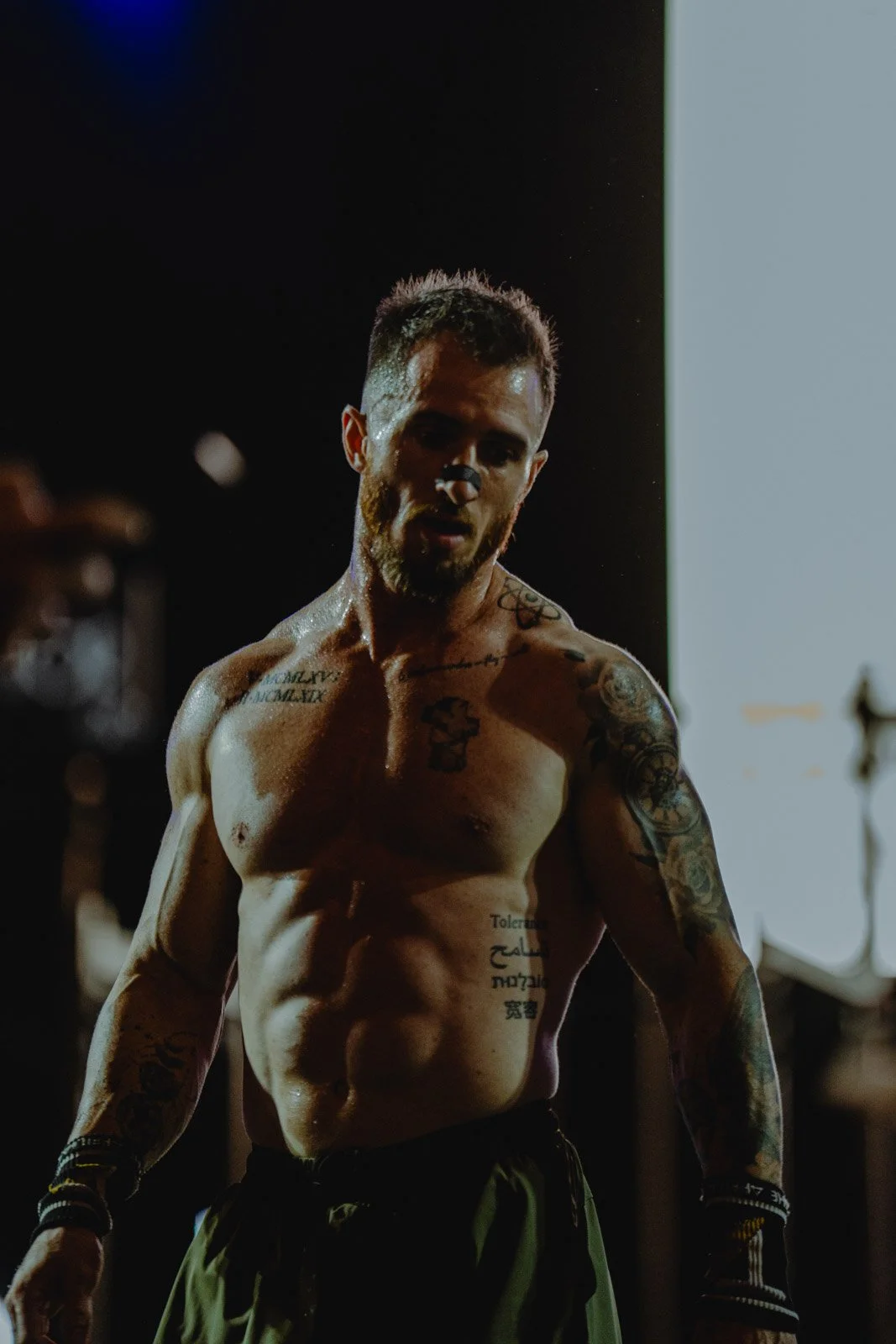 Homme torse nu tatoué sous éclairage ciblé lors d'une compétition CrossFit en Nouvelle-Aquitaine — photographe CrossFit Voar by Tim