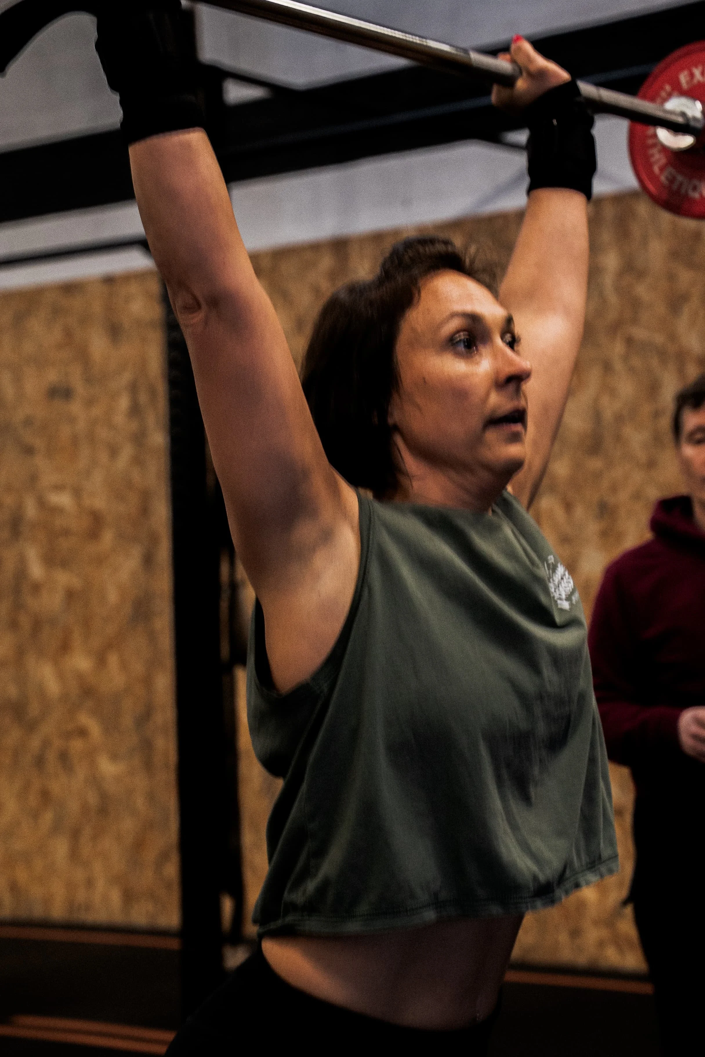 Une femme soulève une barre avec des poids dans une salle de sport.