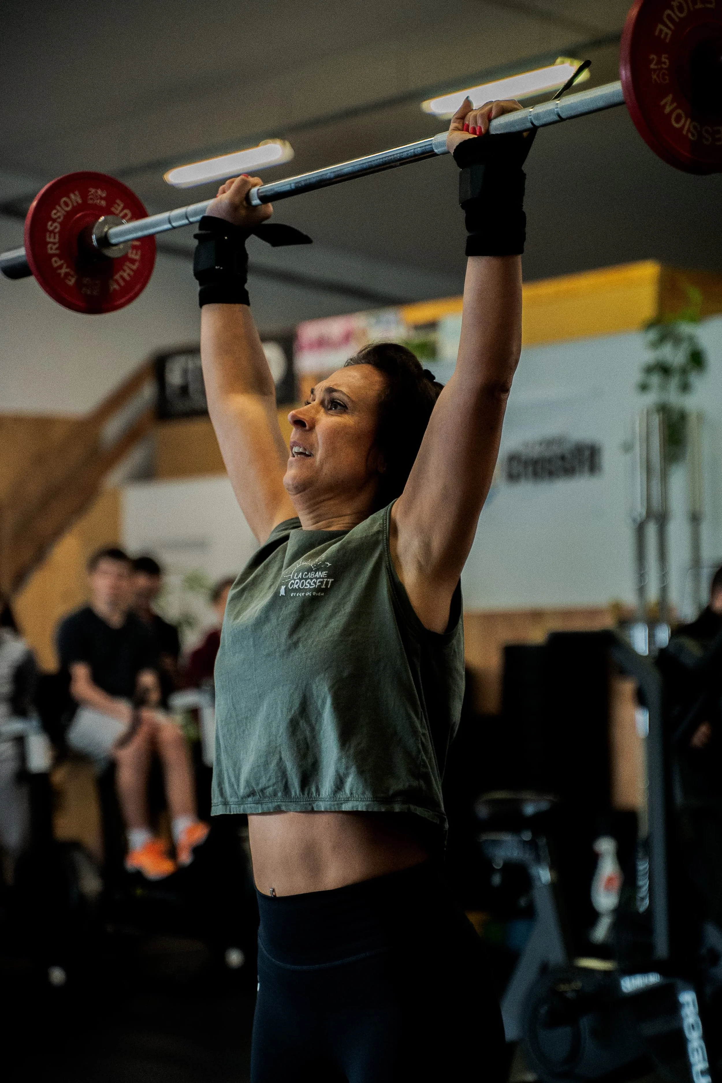 Une femme soulève une barre avec des poids lors d'un entraînement de CrossFit dans une salle de sport