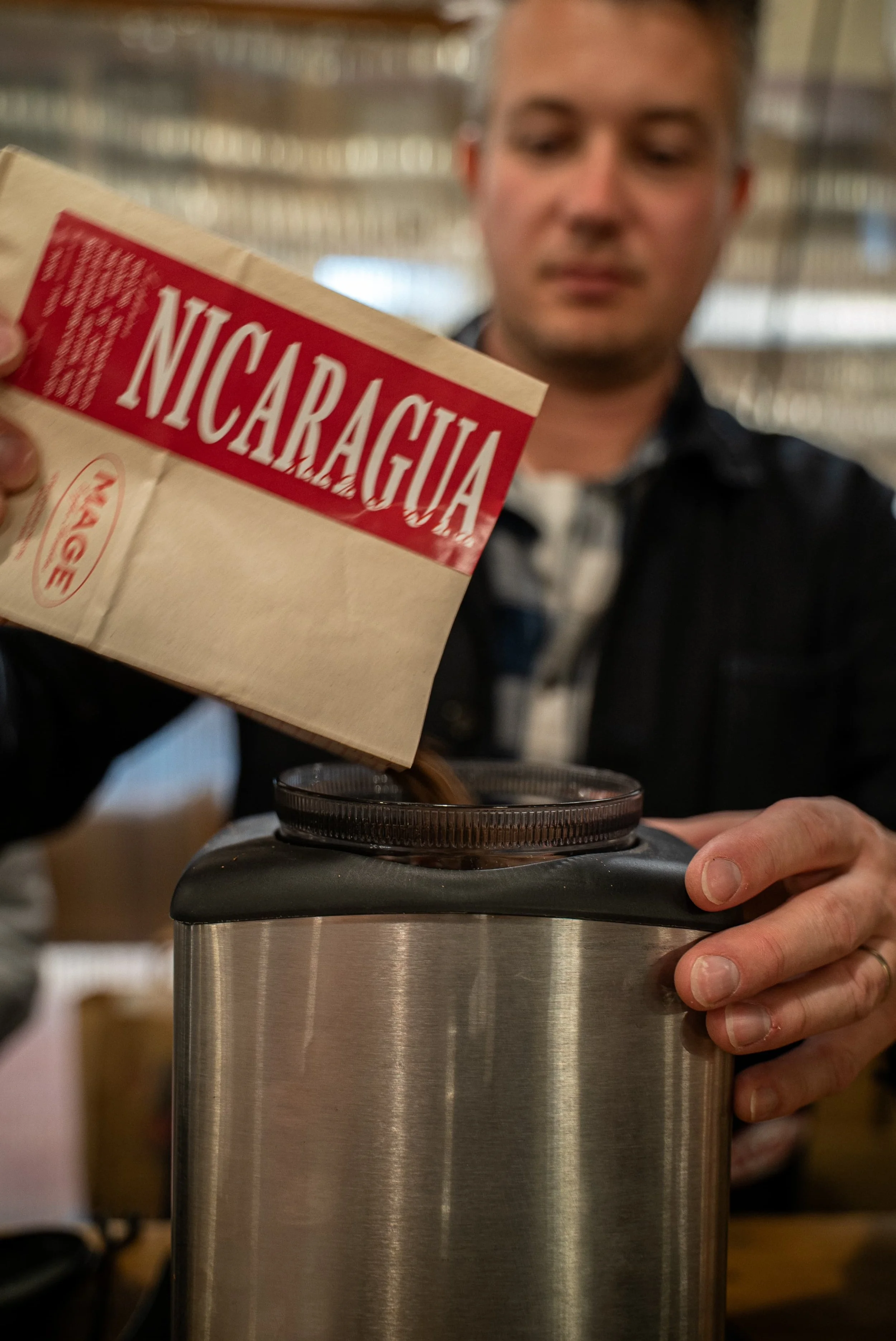 Un homme verse du café d'une boîte de café Nicaragua dans une cafetière électrique.