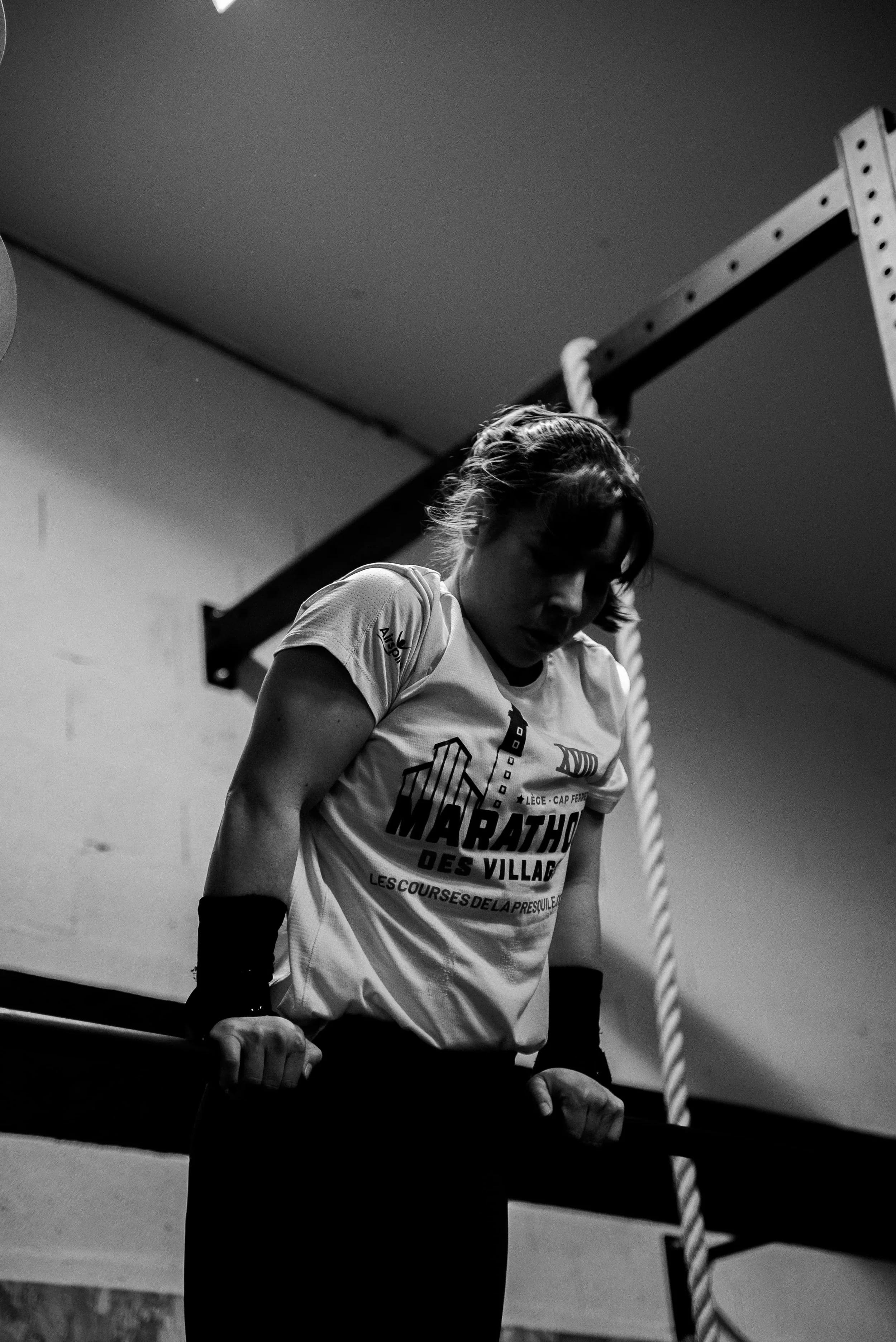 Une femme en t-shirt participe à une épreuve sportive, probablement une course ou un marathon, dans une salle d'intérieur, dans une ambiance de compétition ou d'entraînement.