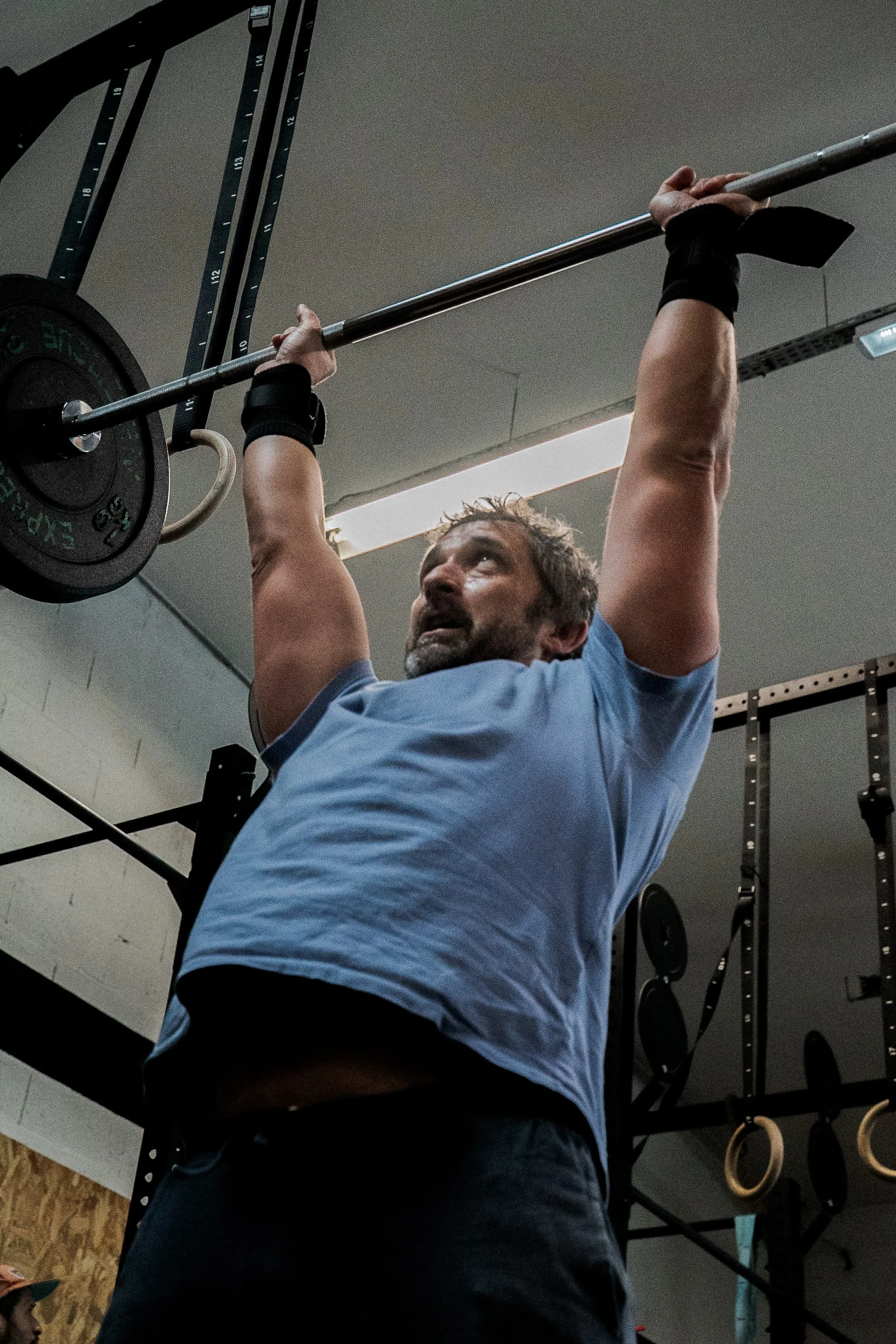 Homme soulevant une barre de poids lors d'un entraînement en salle de sport.