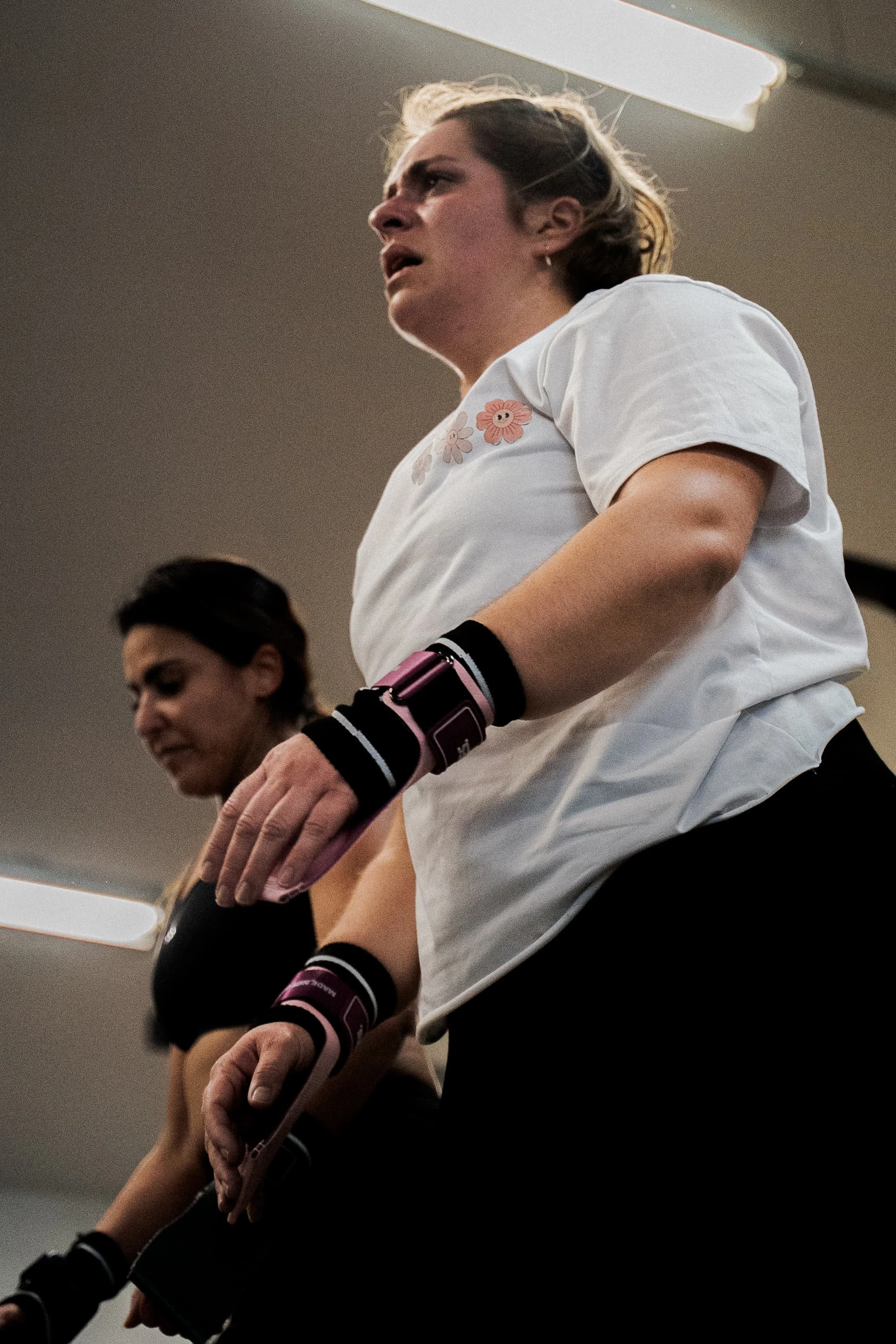 Deux femmes en tenue d'entraînement de boxe, portant des vêtements noirs et des protège-poignets, participant à une séance de boxe en salle.