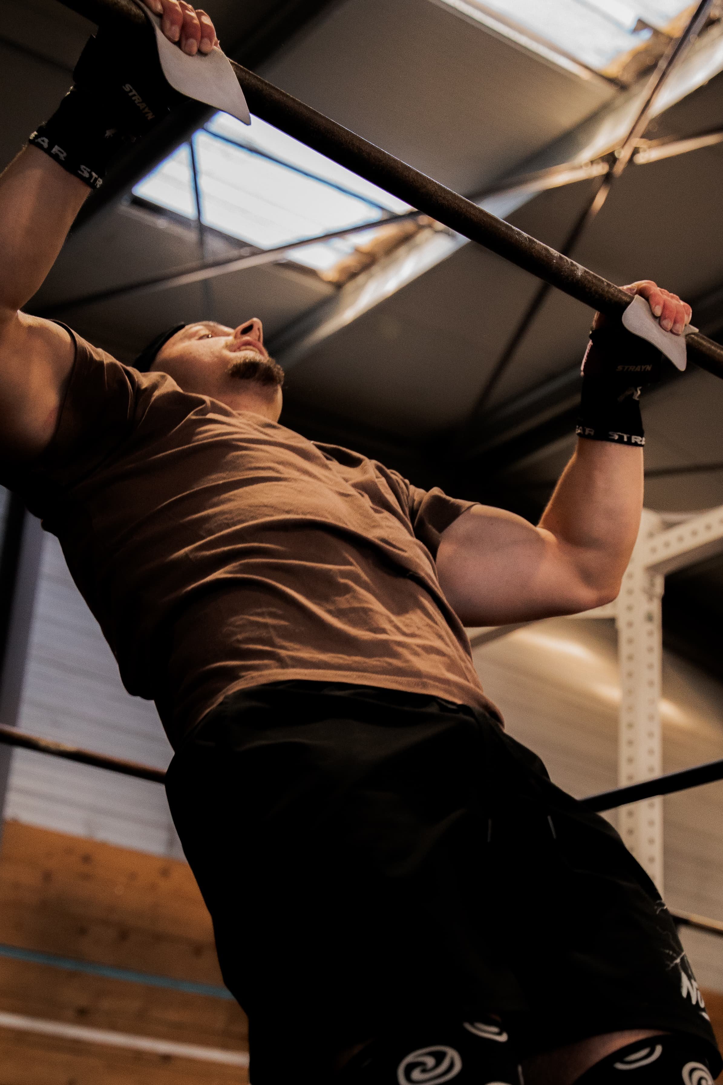 Une personne effectuant un exercice de traction dans une salle de sport, accrochée à une barre de traction.