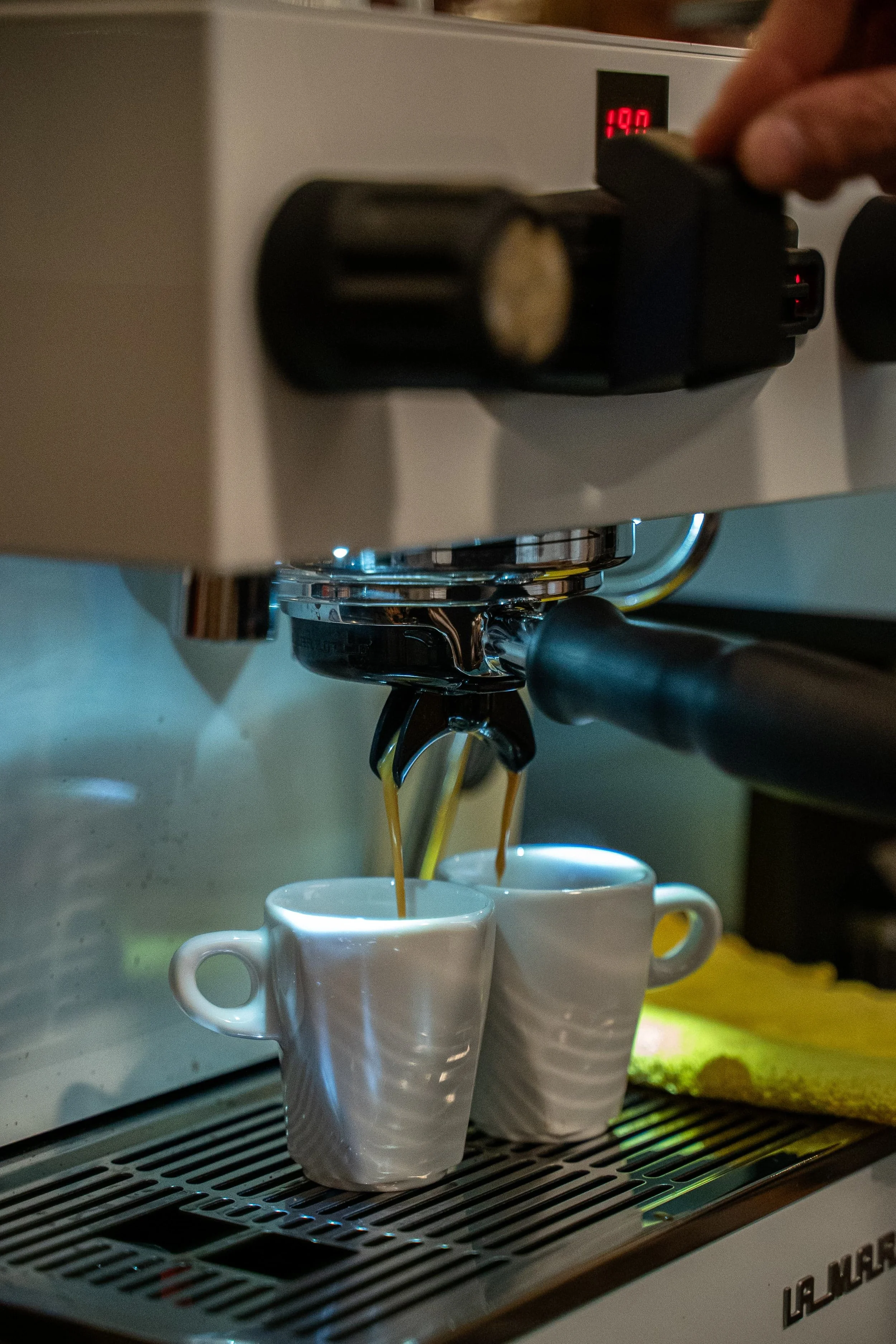 Une machine à café espresso en train de verser du café dans deux tasses blanches.