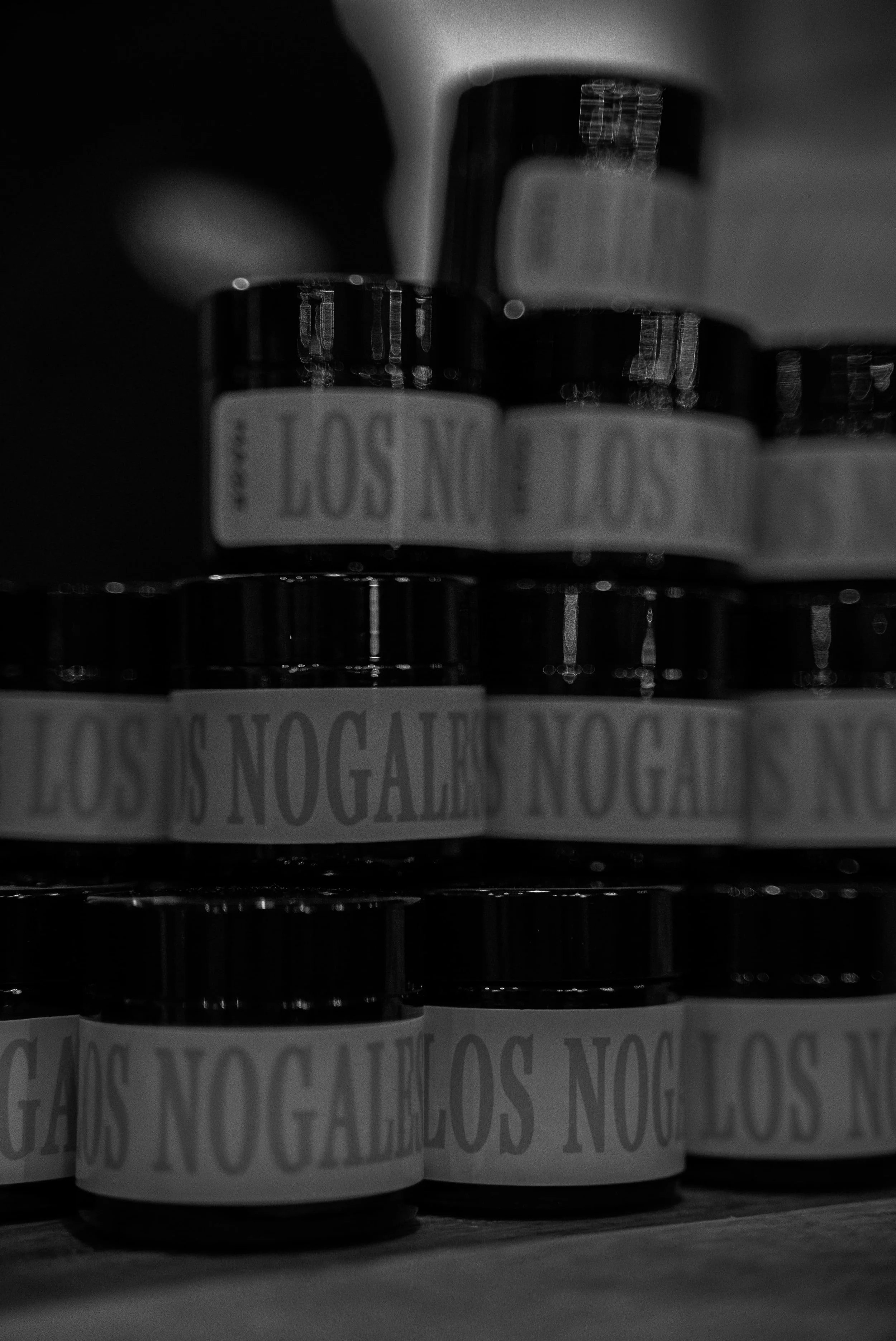 Vieux pots en céramique étiquetés 'LOS NOGALES' en noir et blanc, en rangée sur une étagère en bois